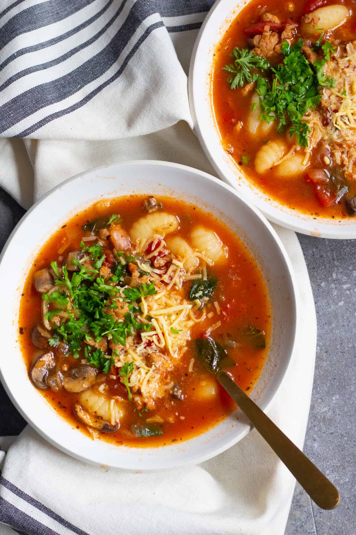 Bowls of Soup with gnocchi topped with Parmesan cheese.