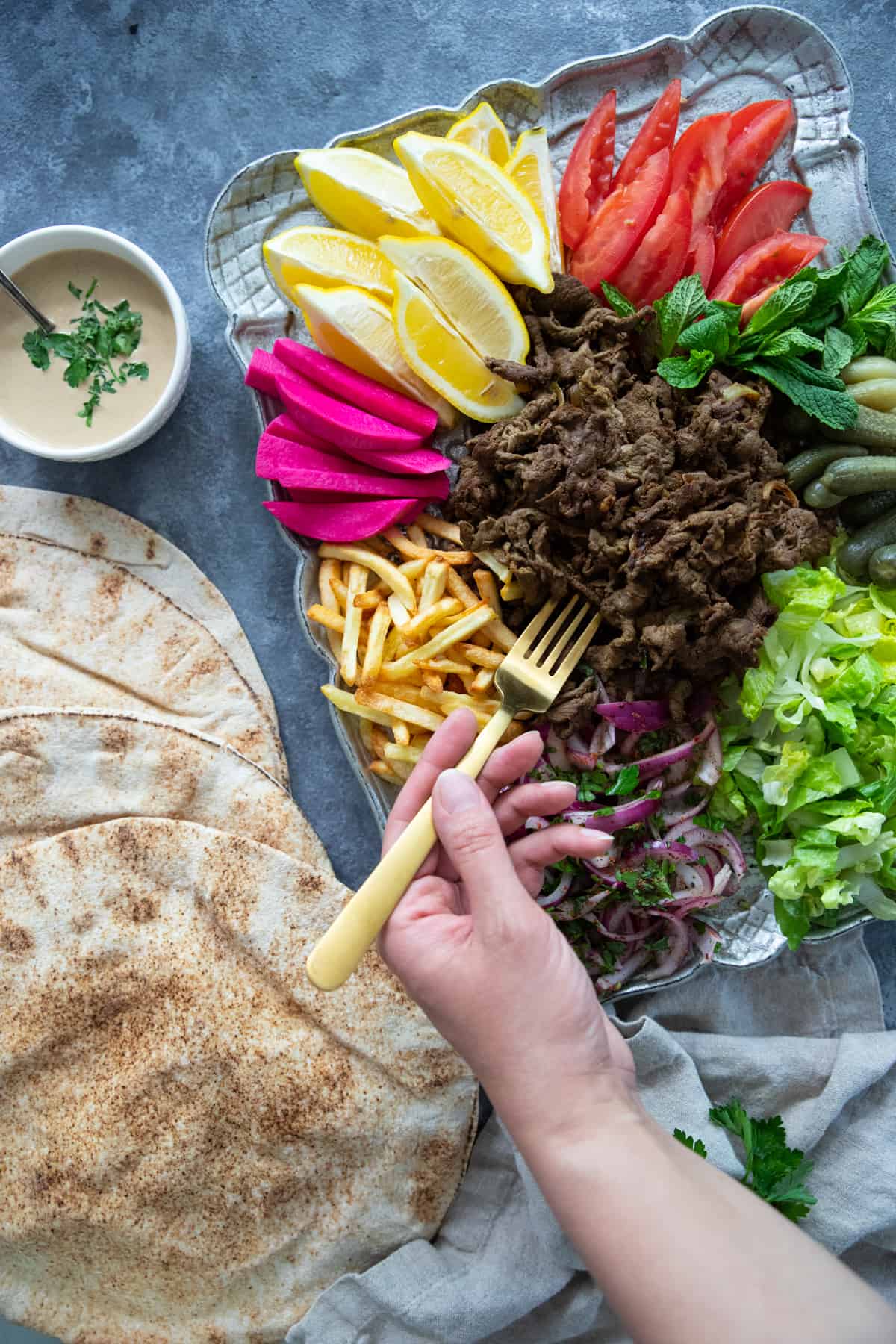 beef shawarma served with pita and fixings. 