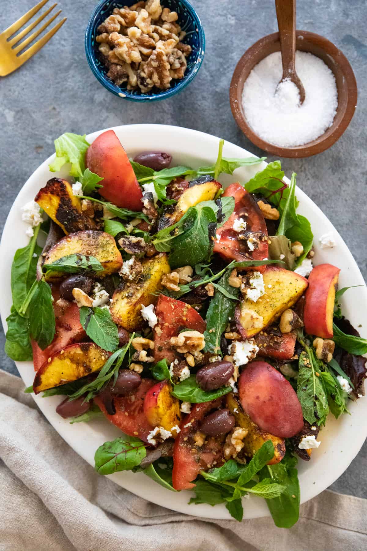 A platter of grilled peach salad on a grey backdrop. 