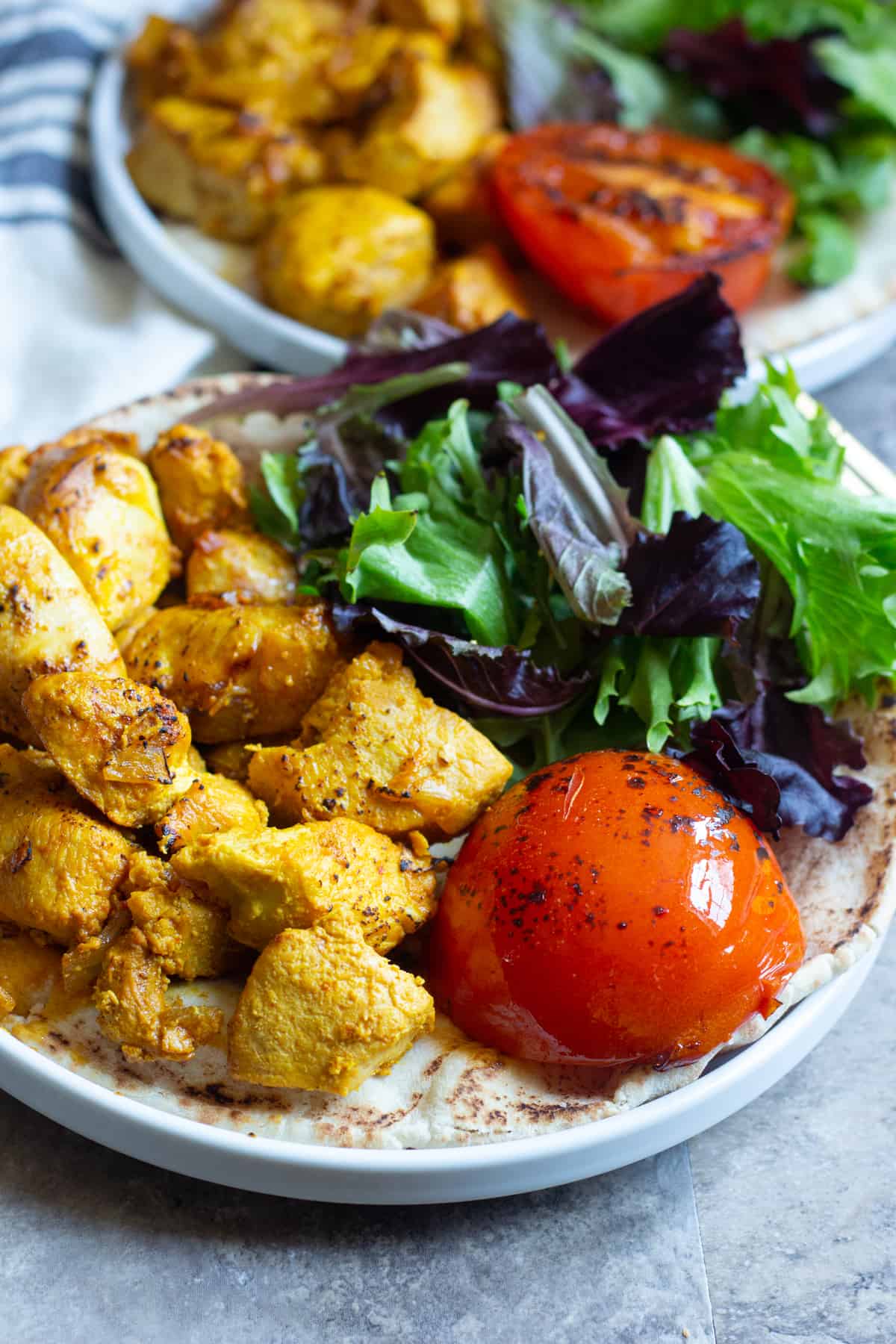 Close up shot of grilled saffron chicken kabobs and grilled tomatoes. 