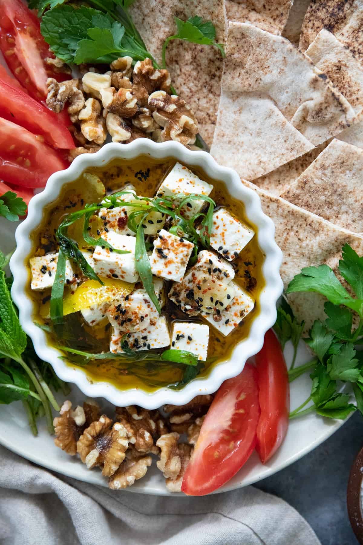 Marinated feta on a platter with veggies and bread. 