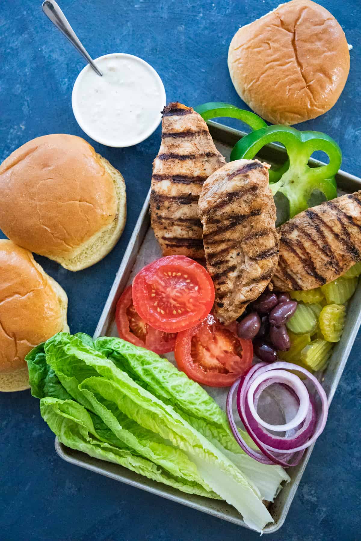 grilled chicken and vegetables on a baking sheet with brioche buns. 
