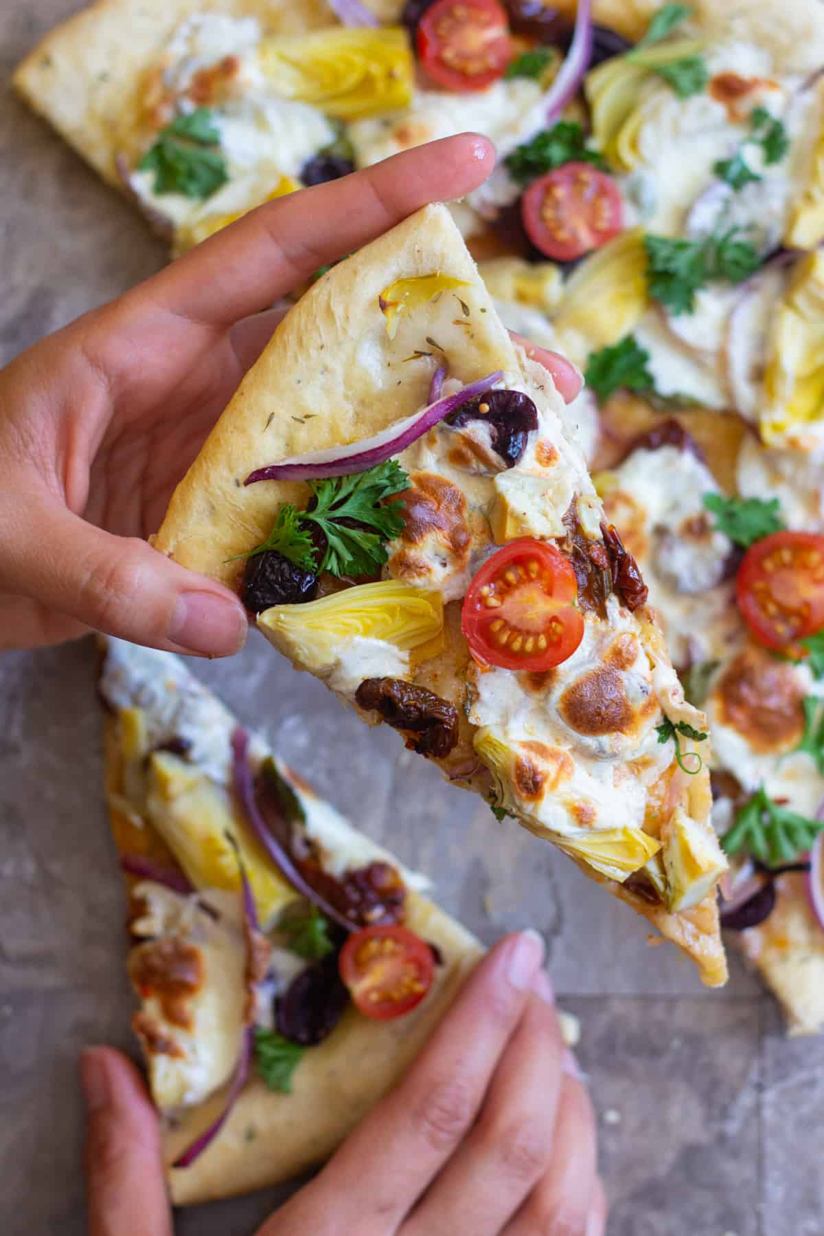 A slice of Mediterranean pizza topped with cherry tomatoes. 