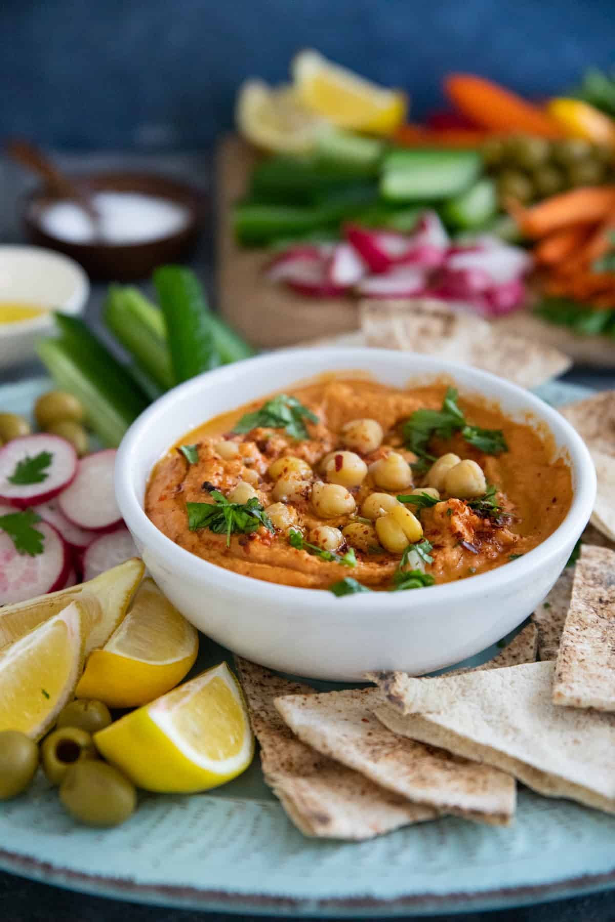 white bowl with roasted red pepper hummus topped with chickpeas 