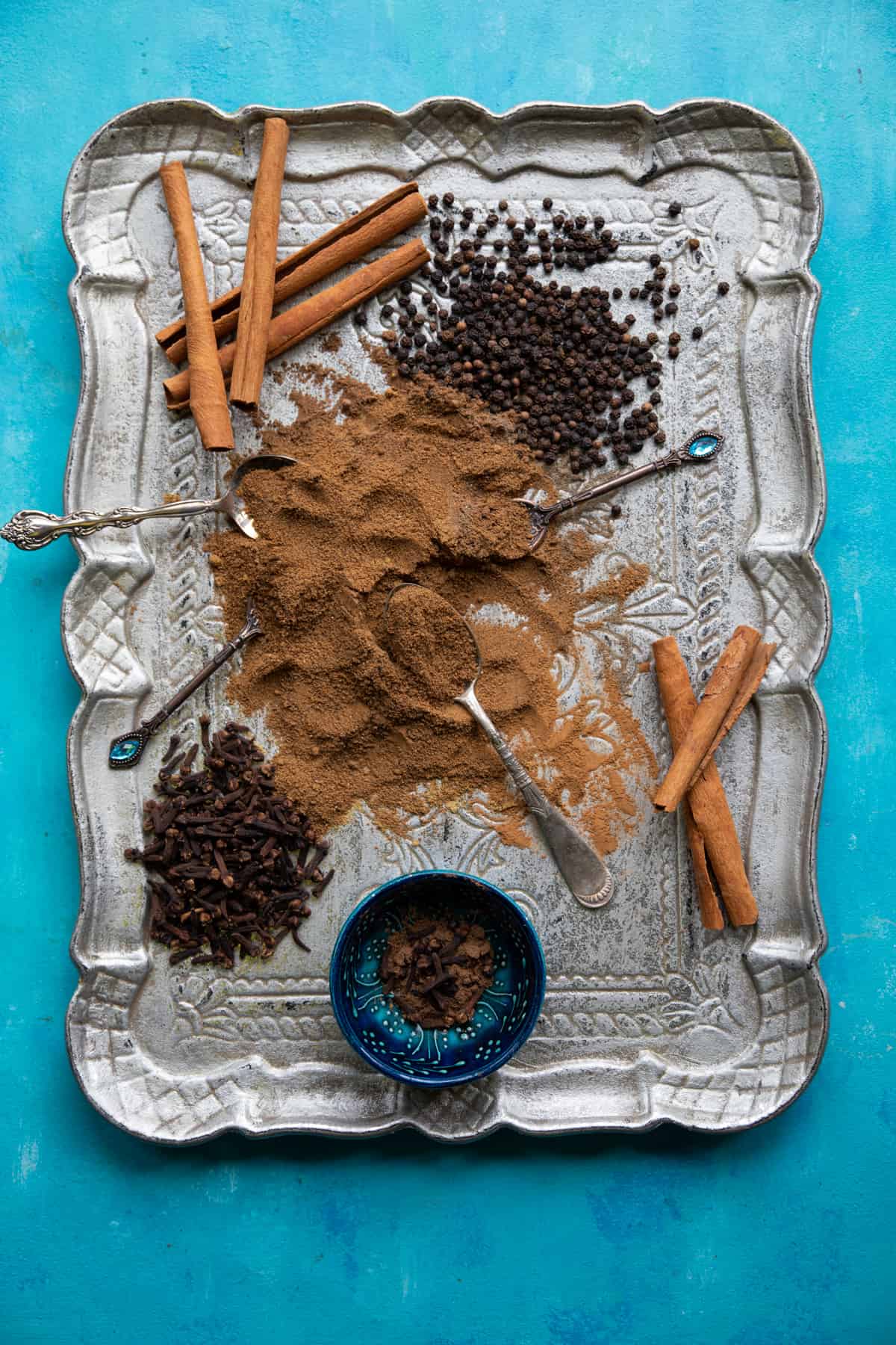 overhead shot of seven spice mix on a tray with whole spices. 