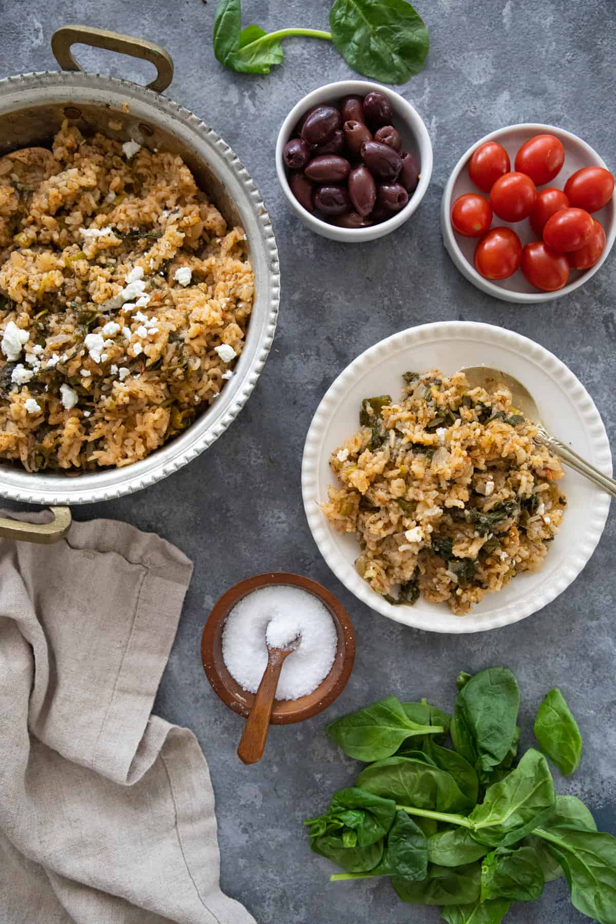 A plate and platter of Greek spinach rice for fall dinner with olives and tomatoes. 