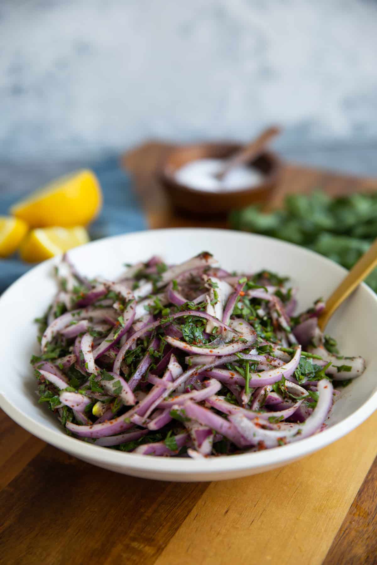 a bowl of red onion and sumac on a wooden board. 