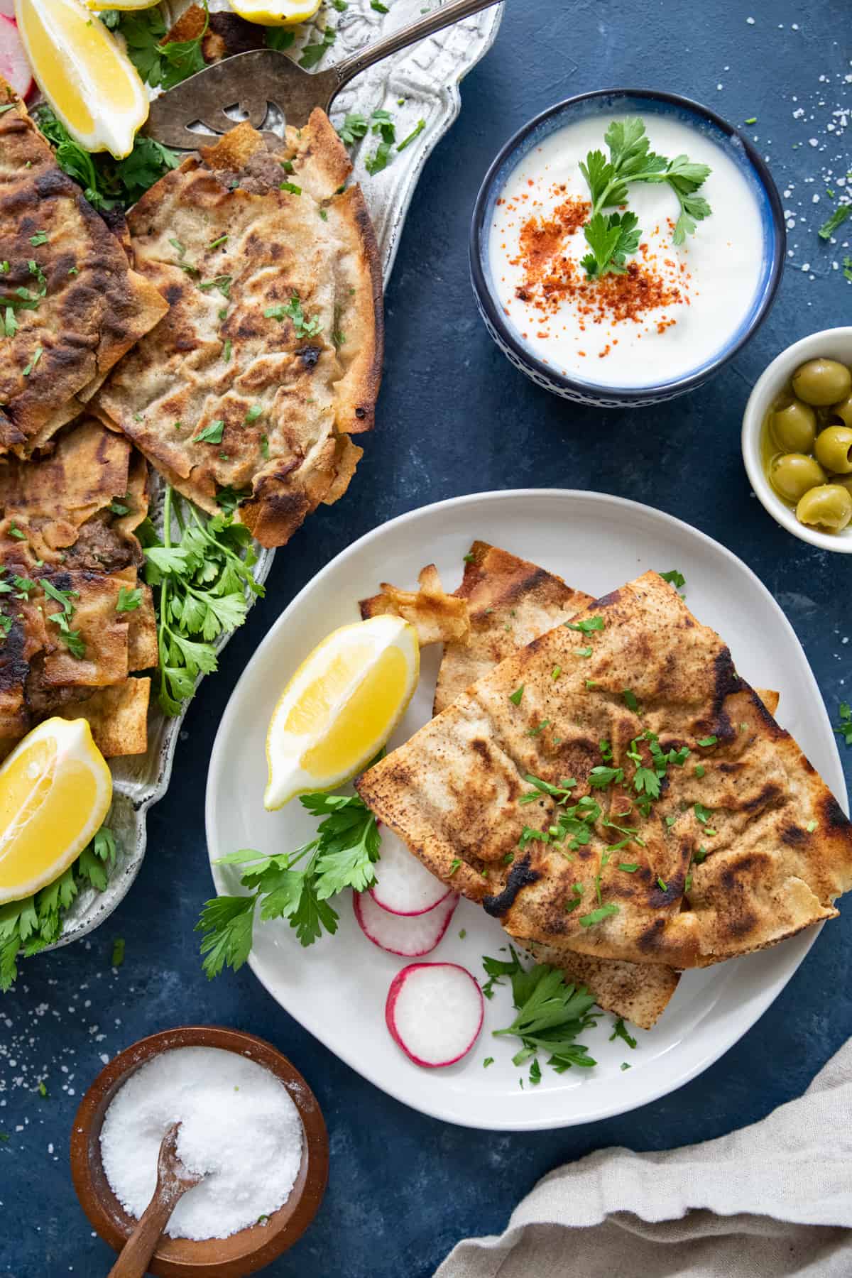 a plate of arayes with vegetables next to a platter on a dark blue backdrop. 