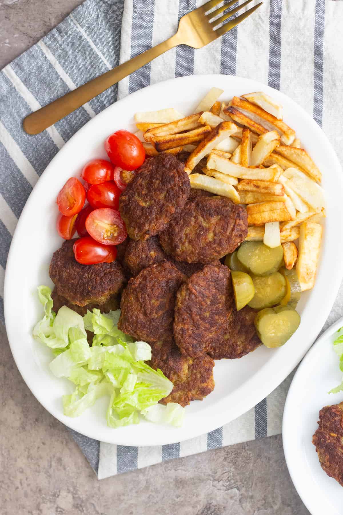Serve kotlet with French fries, tomatoes and pickles. 