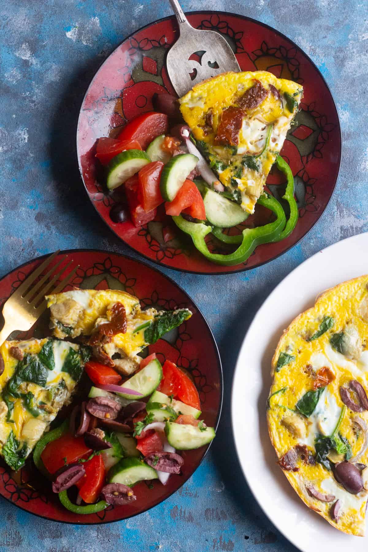 Two red plates and one white plate with omelette on a blue background.