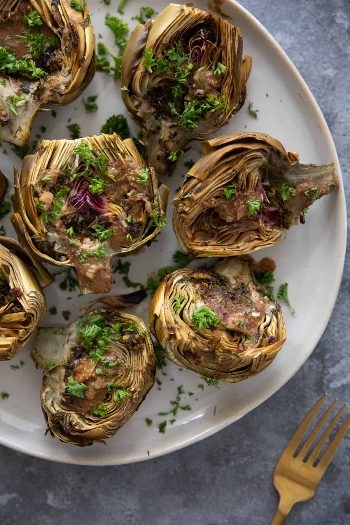 Overhead shot of roasted artichokes topped with parsley. 