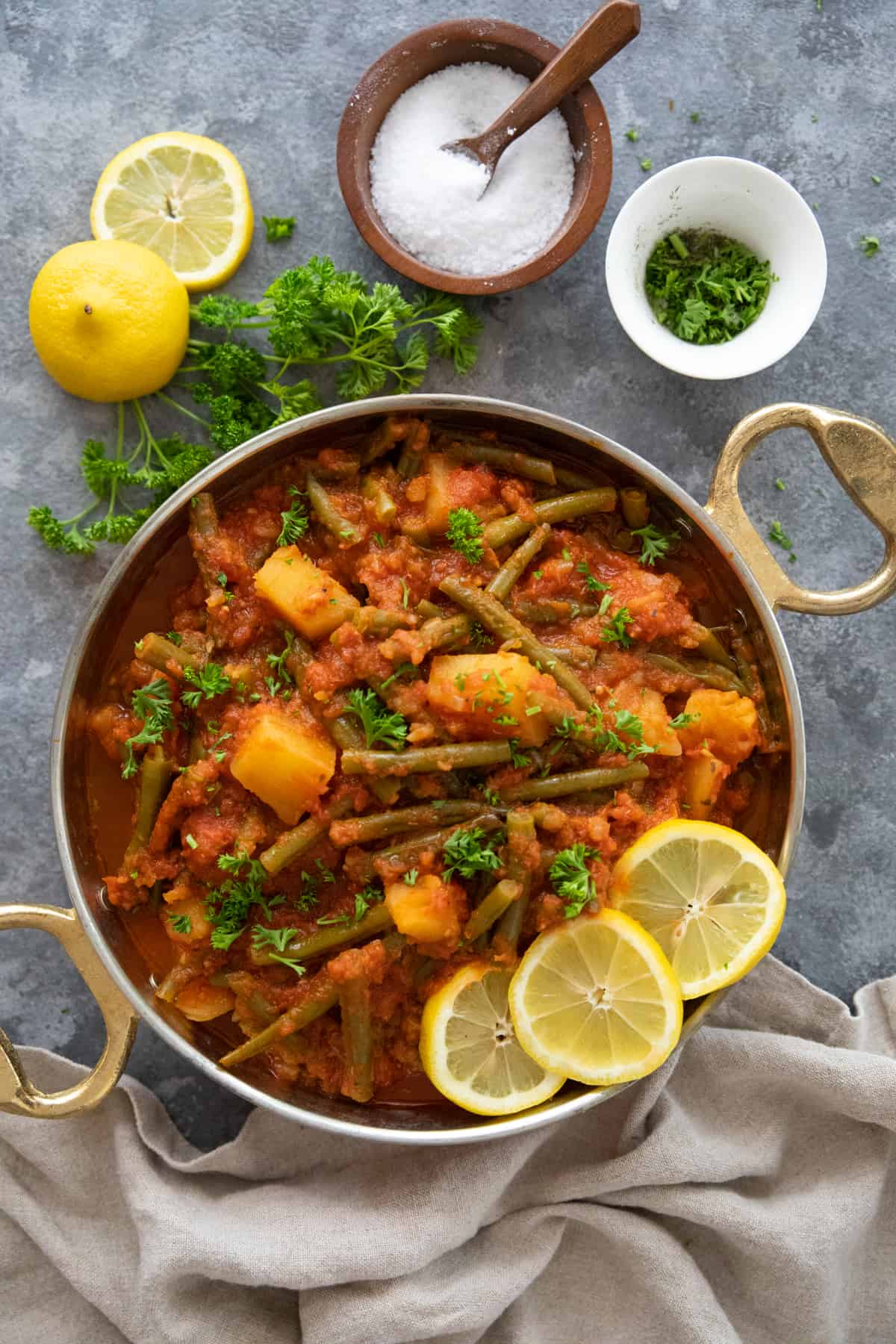 Overhead shot of fasolakia with salt, parsley and lemons. 