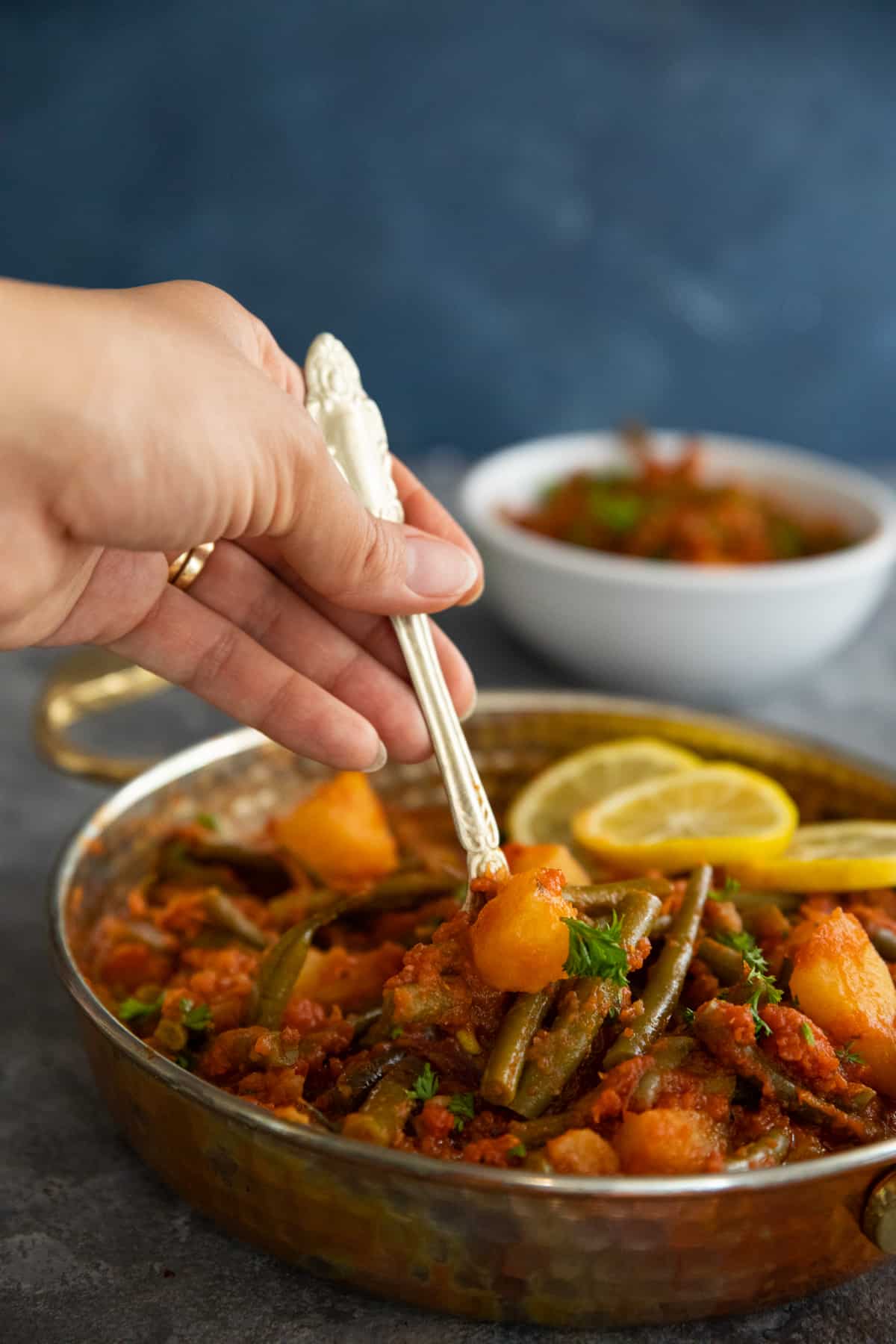 close up shot of fasolakia in a pan. A hand picking some up using a fork. 