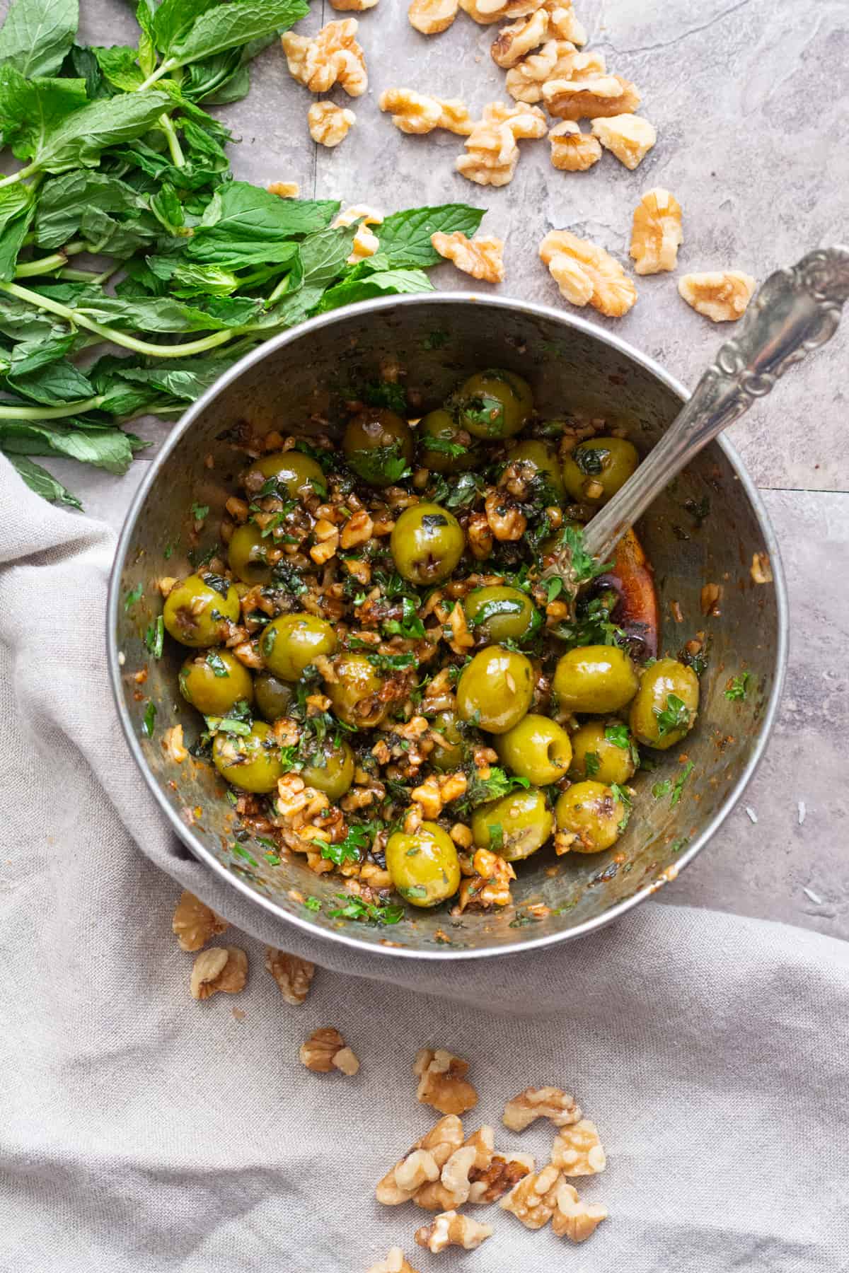 To make marinated olives. you need olives, walnuts, pomegranate molasses, garlic, extra virgin olive oil and mint.