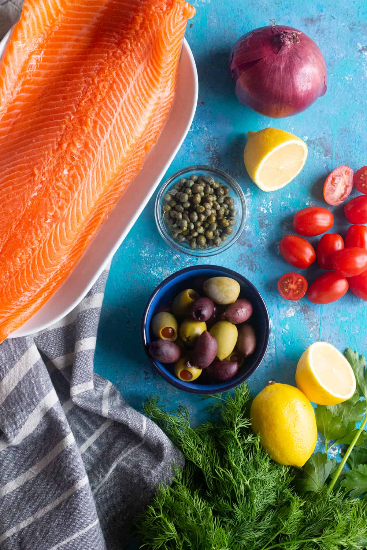 To make baked salmon, you need a side of salmon, olives, lemon, onion and tomatoes