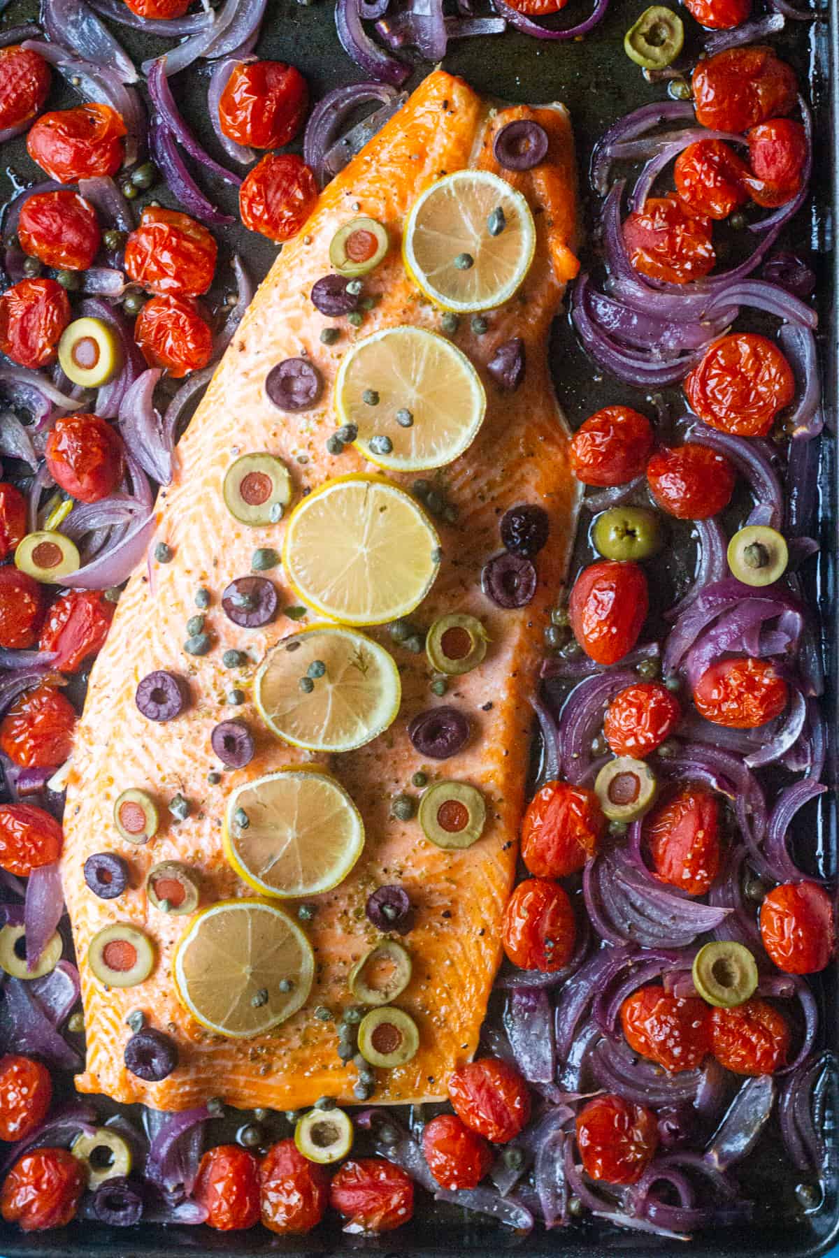 Place salmon on the baking sheet and top with lemon and capers and olives. Bake with tomatoes and onions. 