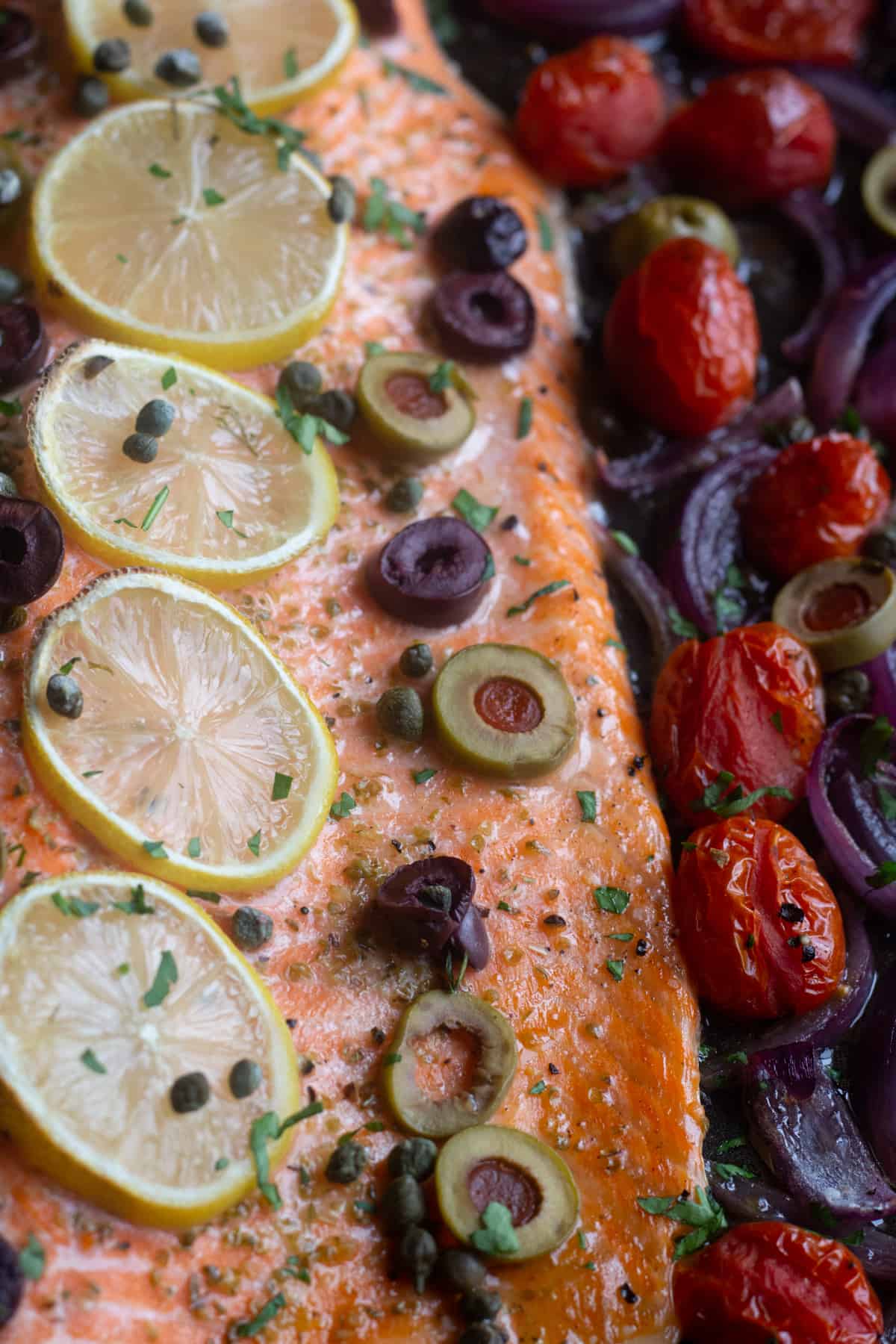 The best ever oven baked salmon is here! Flaky and moist Alaska salmon with olives and capers on a bed of vegetables is an outstanding choice for your weeknight dinner.