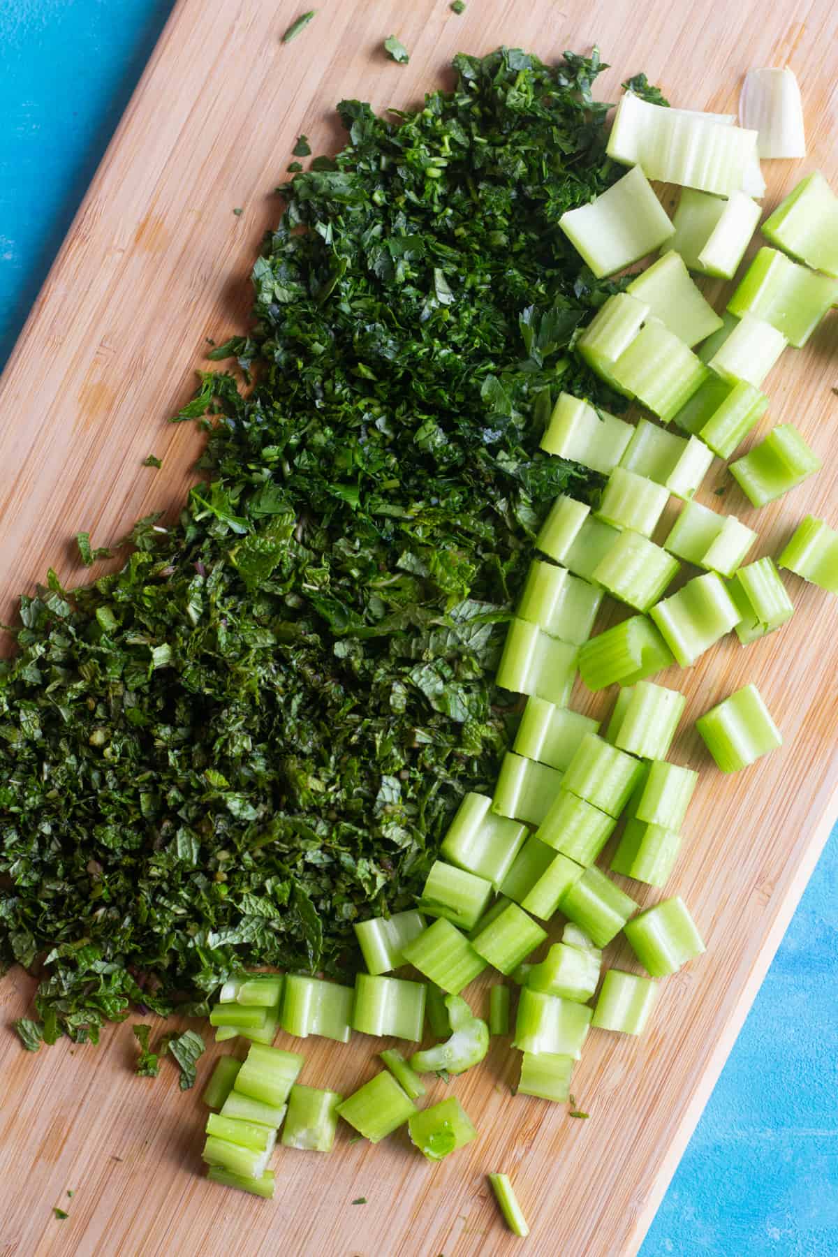 chop parsley, mint and celery on a chopping board. 