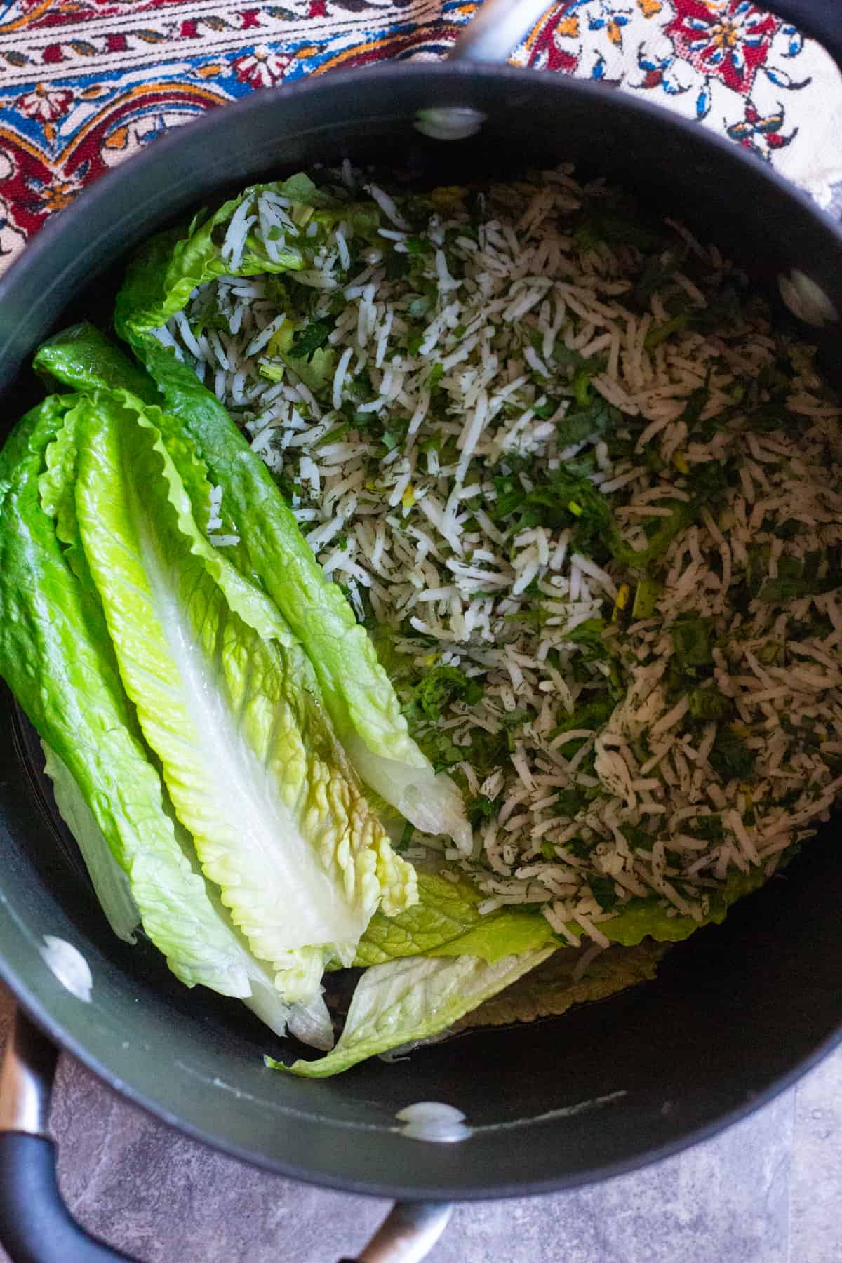 Cover the bottom of the pot with oil and lay lettuce leaves at the bottom of the pot. Scoop in the rice and herb mixture. 