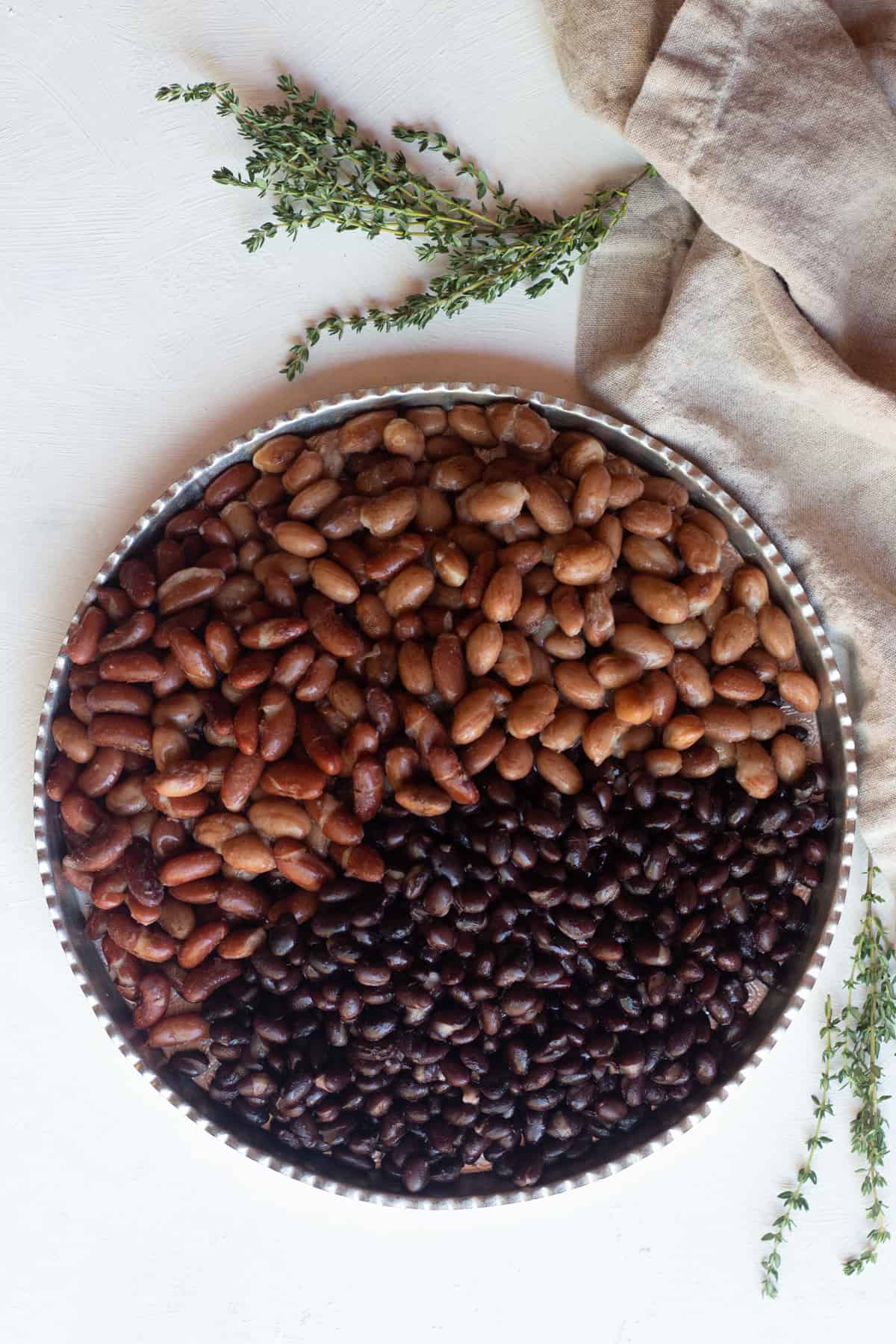 A serving tray with three types of beans, red kidney beans, pinto beans and black beans.