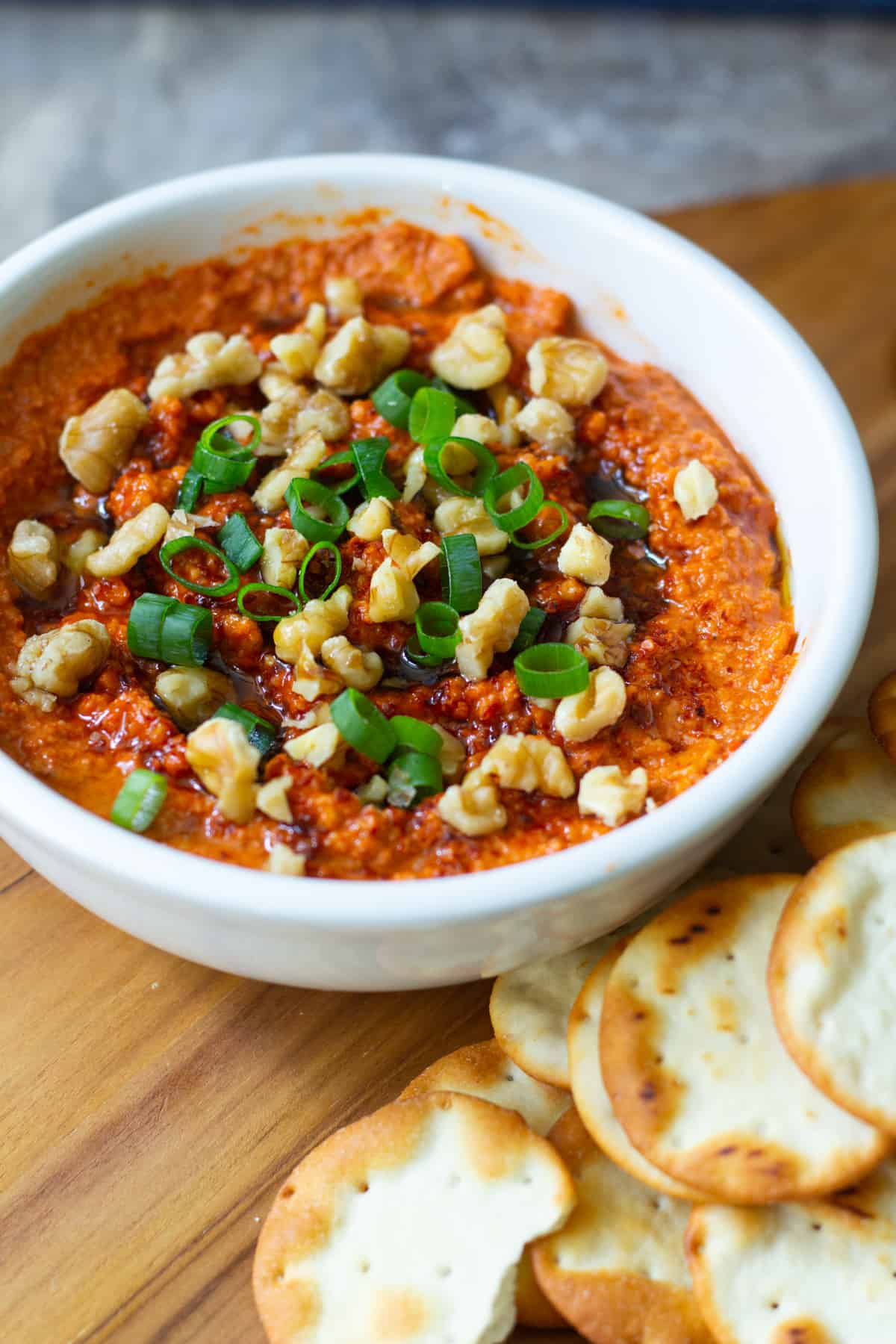 Top roasted red pepper and walnut dip with walnuts and green onions. 