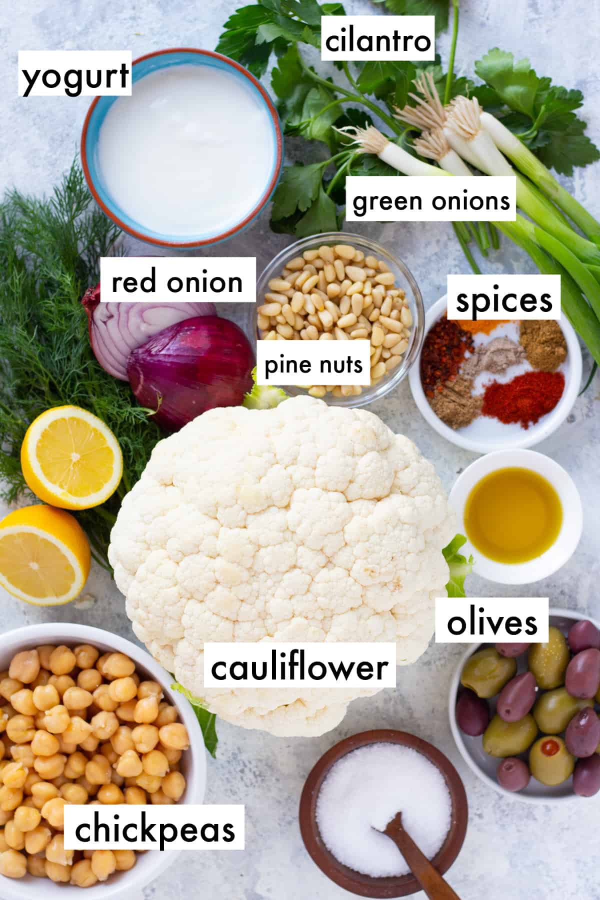 To make this salad you need cauliflower, spices, chickpeas, olives, olive oil, pine nuts, red onion, lemon, yogurt and herbs.