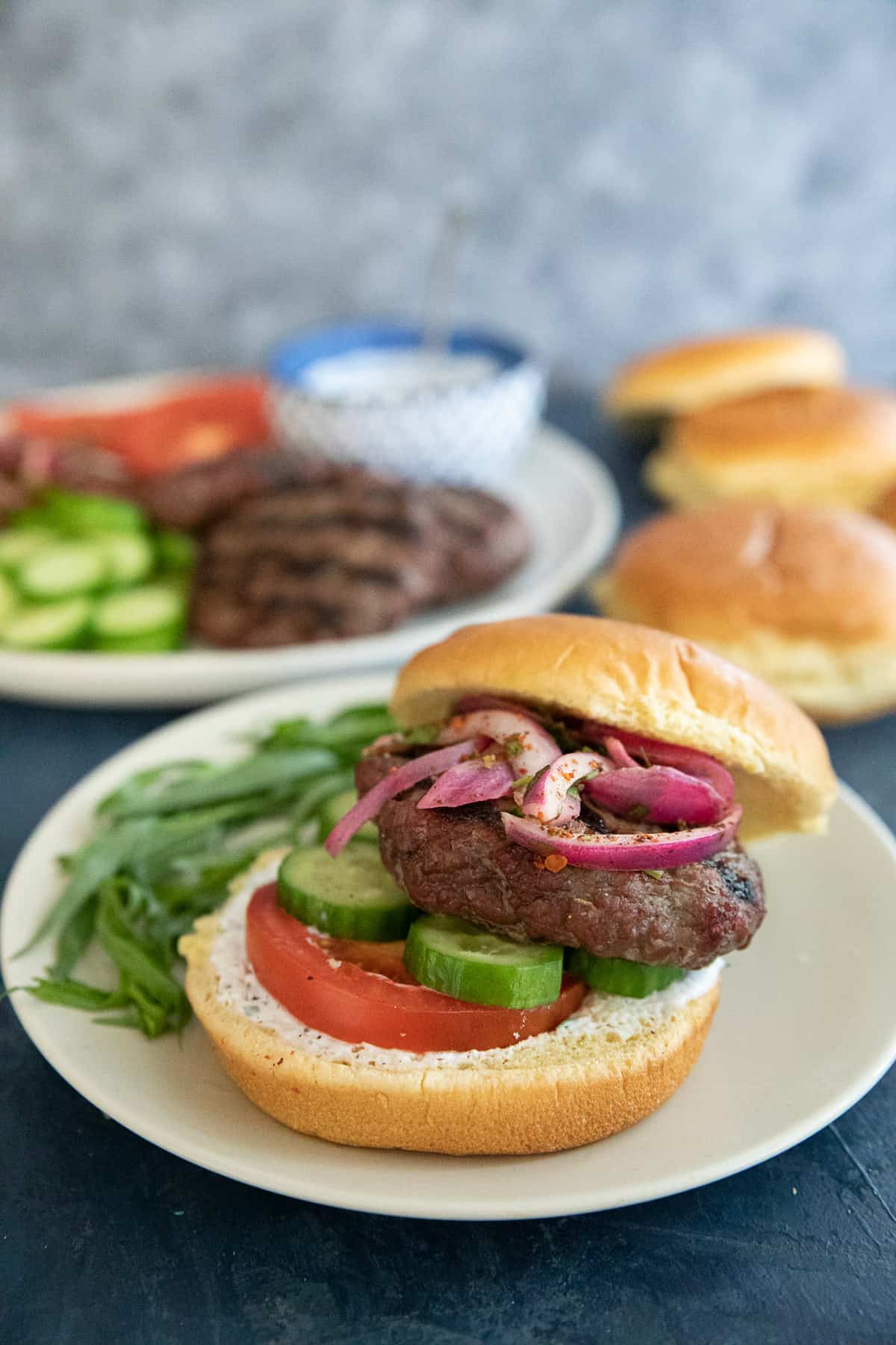 burger patty on a bun with vegetables.