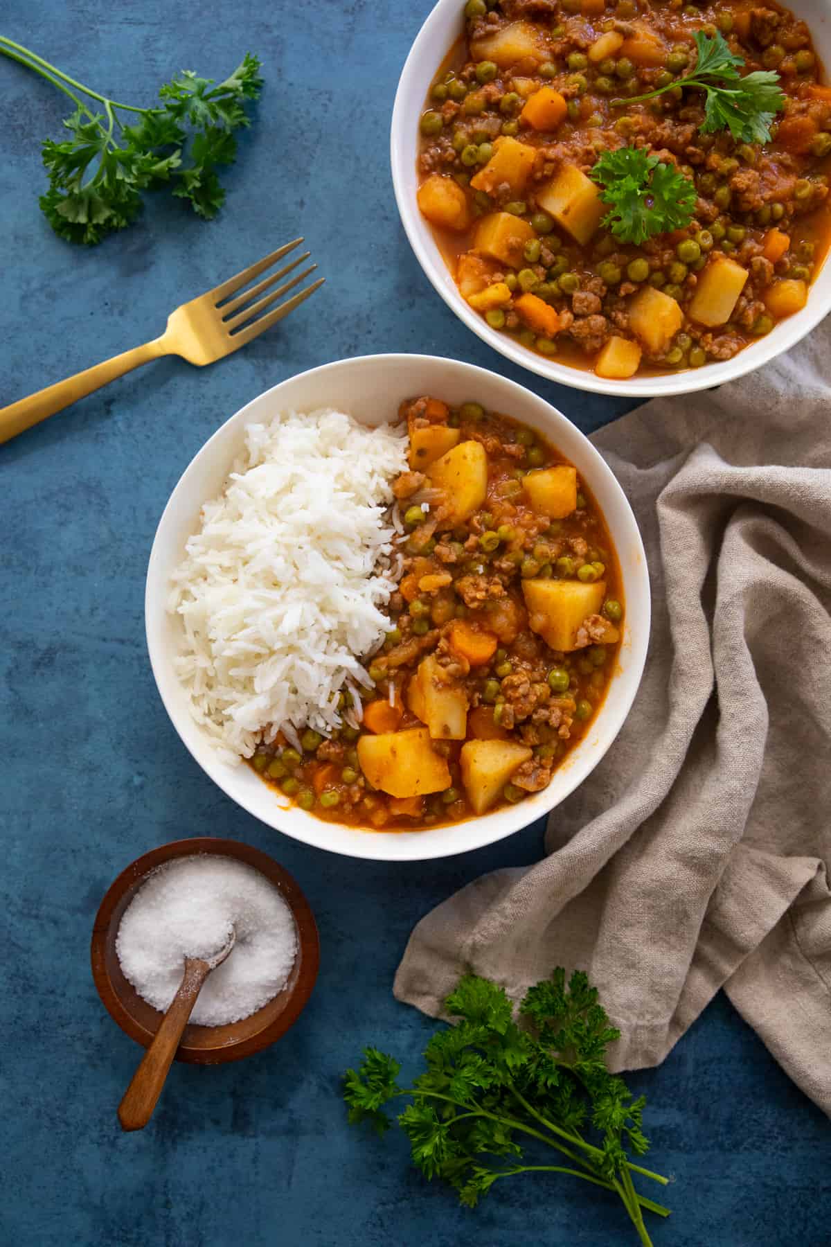 ground beef stew served with rice and on its own on a blue backdrop. 