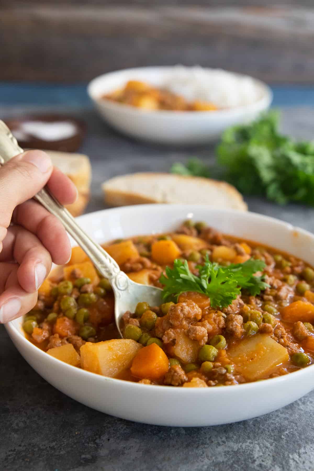 ground beef stew with a spoon in a white bowl.