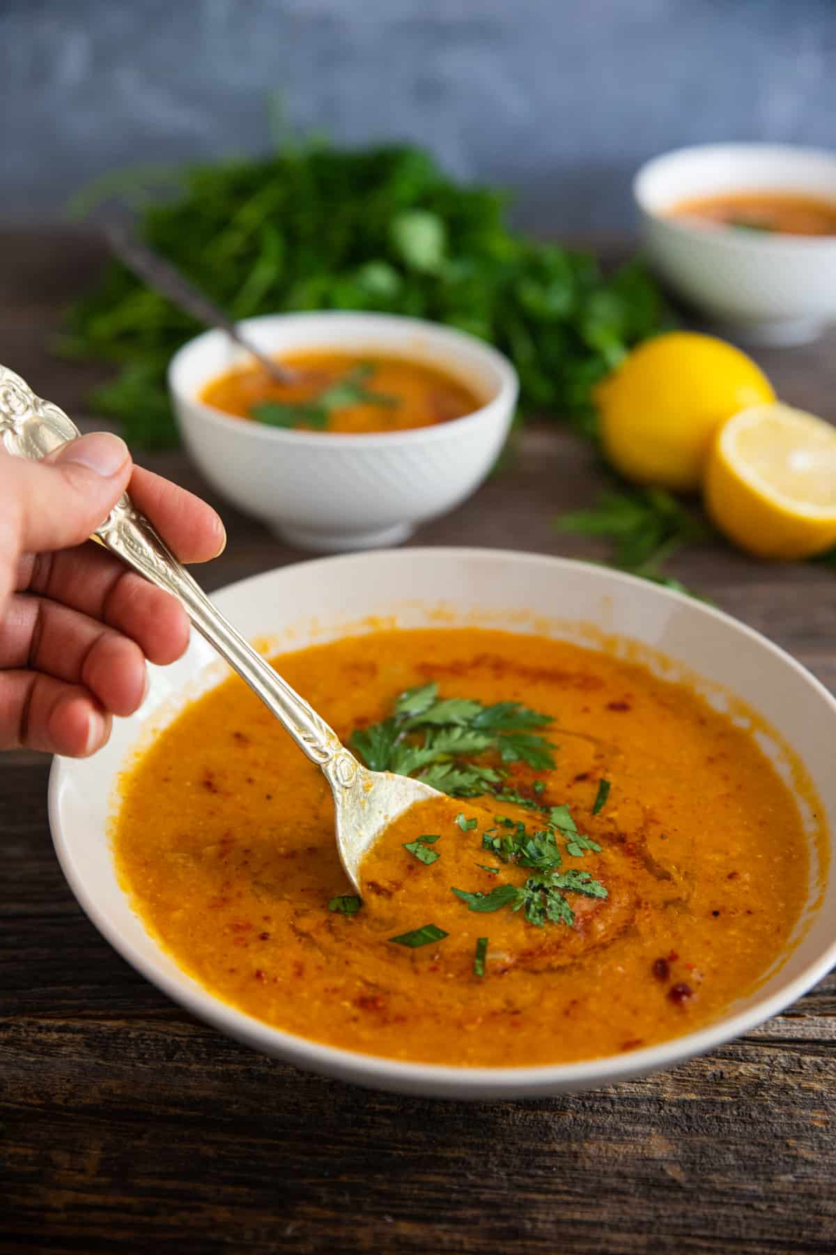a spoon into the red lentil soup topped with olive oil and pepper.