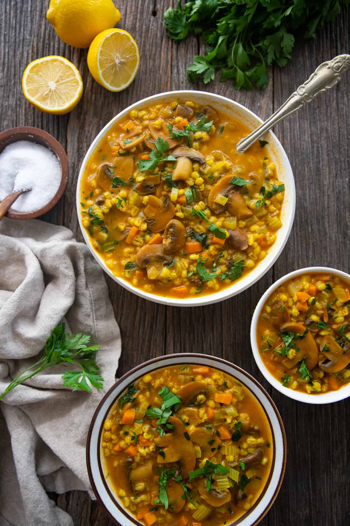 three bowls of soup on a wooden surface.