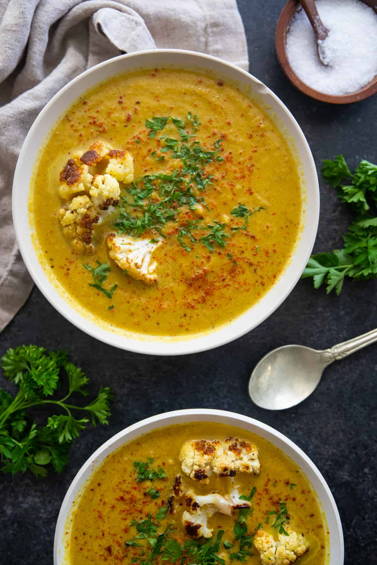 two bowls of soup topped with cauliflower. 