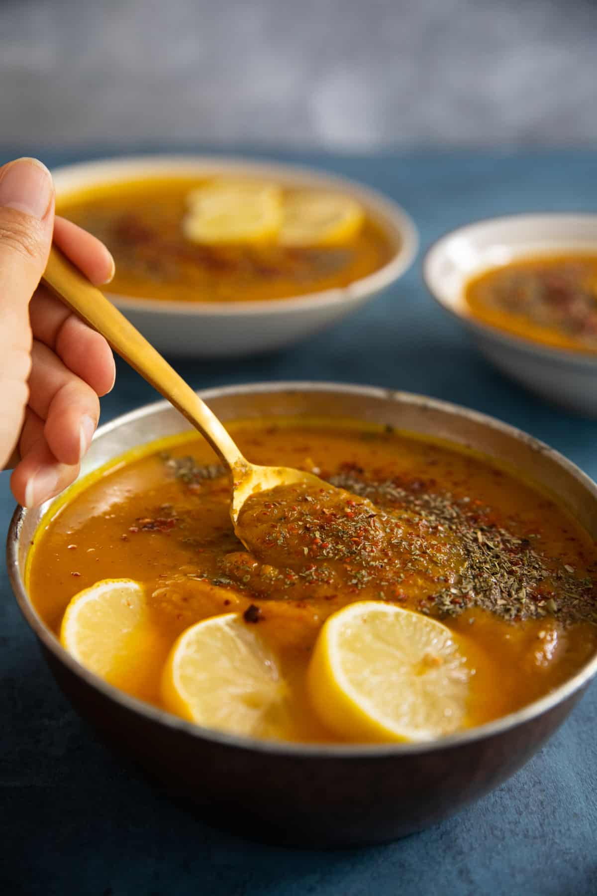 closeup shot of soup in a bowl topped with dried mint, lemon and pepper. 