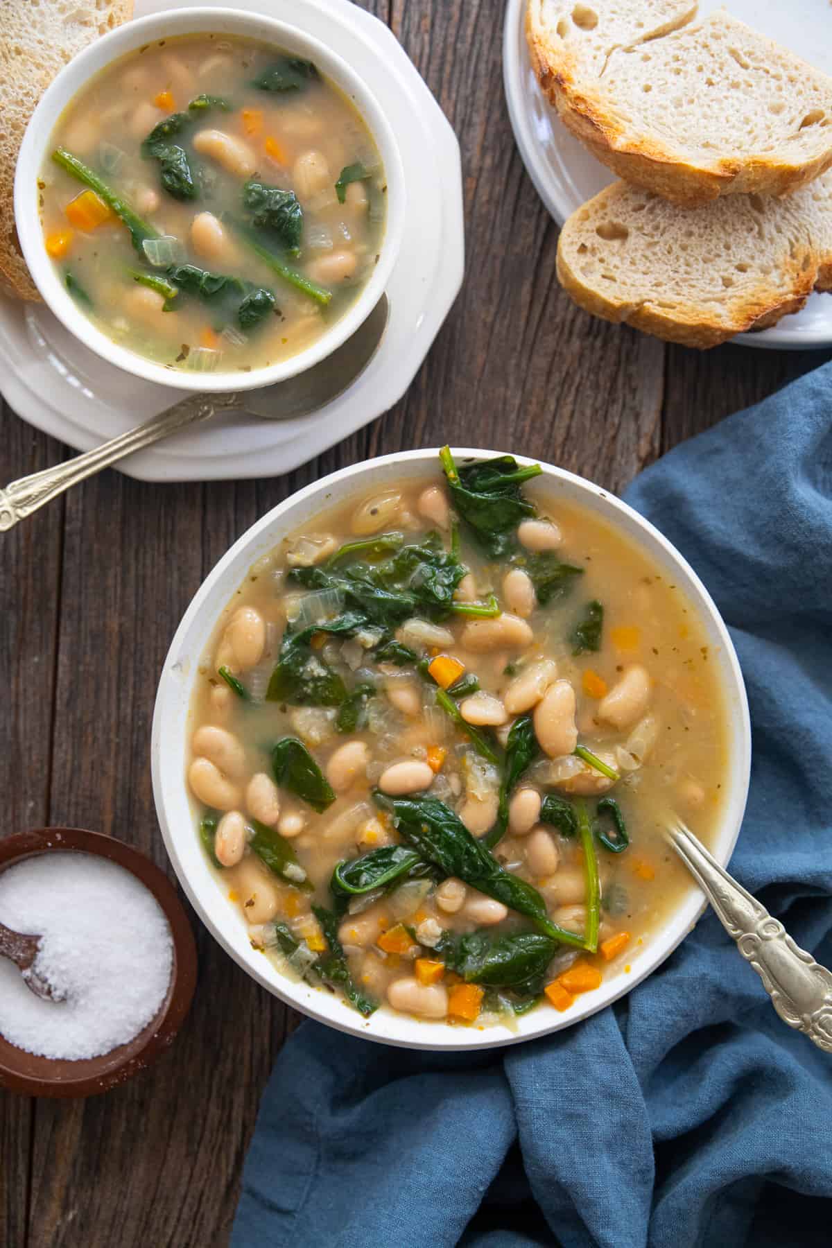 two bowls of white bean soup on a wooden backdrop. 