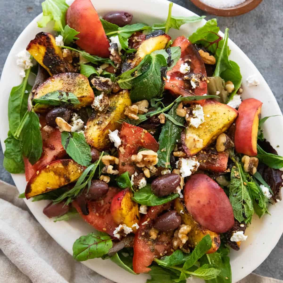 Ready in 20 minutes, this grilled peach salad recipe is a versatile option for adding bold flavors to your lunch or dinner table. Juicy peaches are grilled, added to greens, and then topped with feta, zaatar and walnuts to make a delicious salad.
