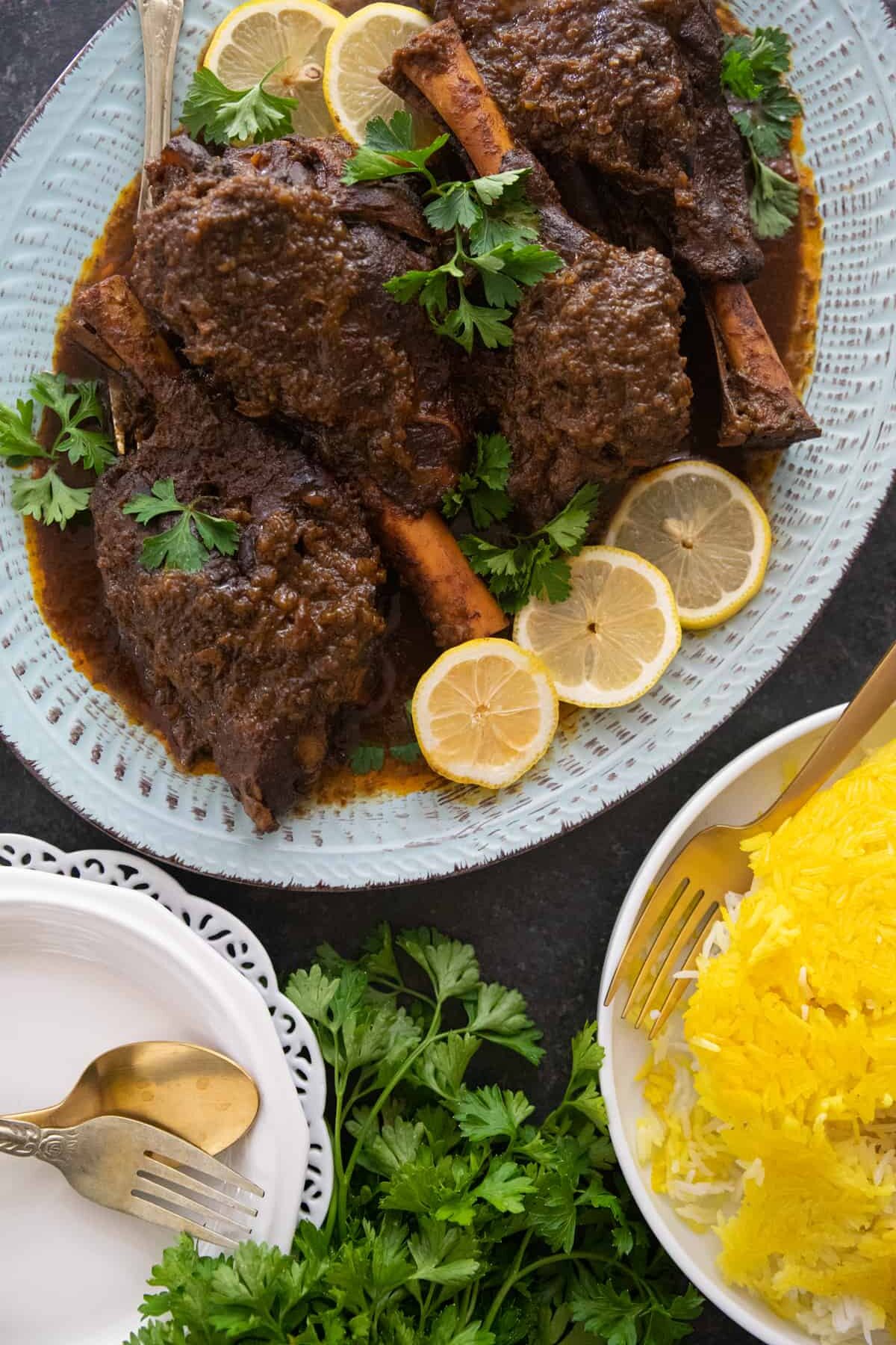 braised lamb shanks on a blue platter with rice.