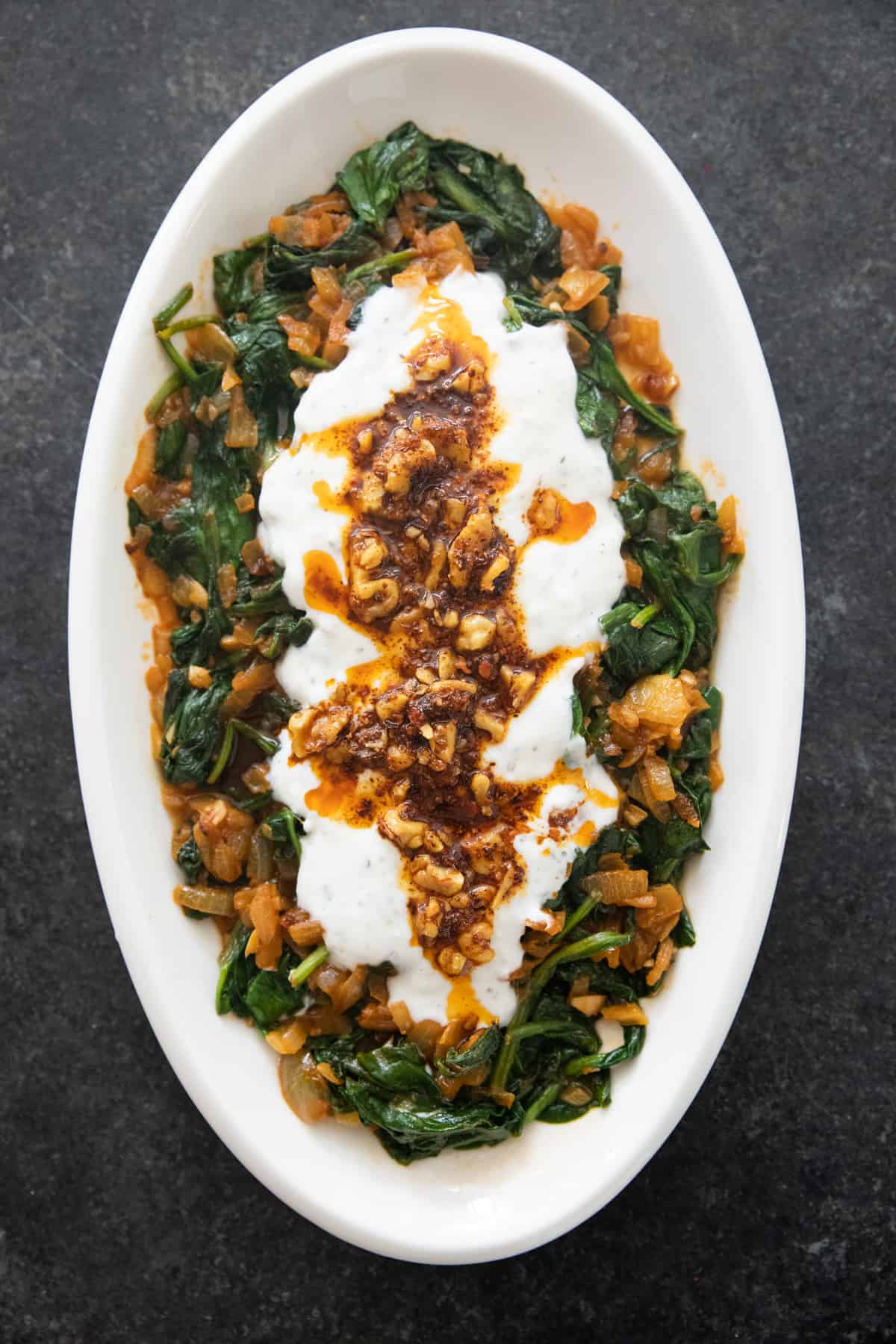 overhead shot of sauteed spinach with yogurt sauce on a plate. 