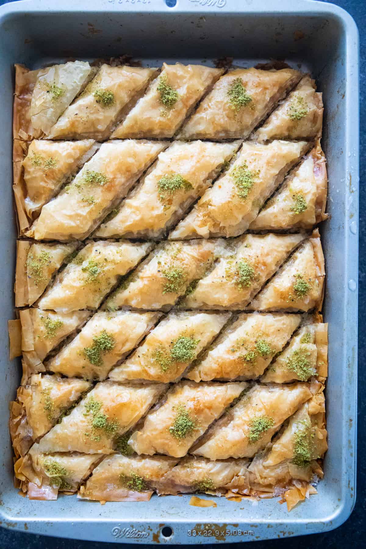 a pan of baklava topped with pistachios. 