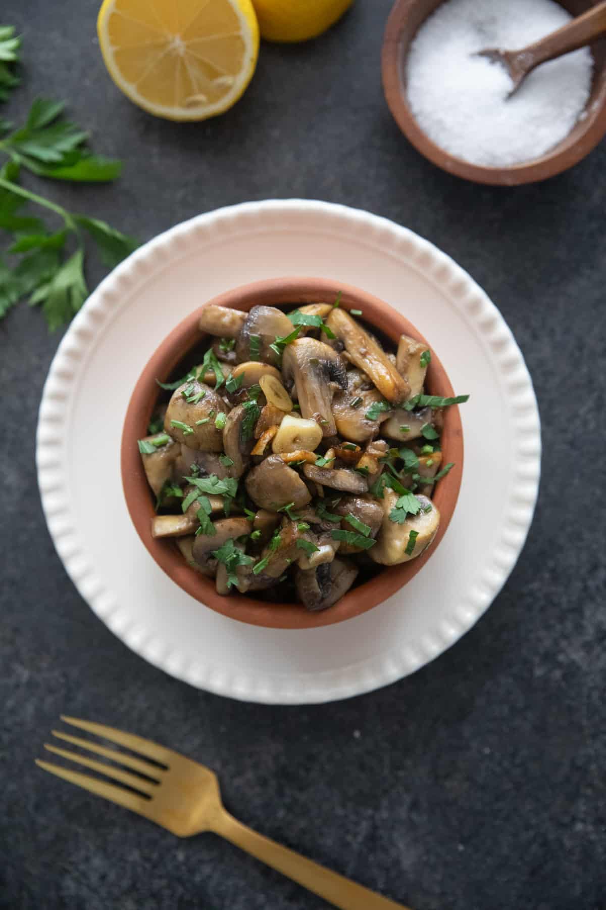 garlic mushrooms champiniones al ajillo in a clay pot on a black backdrop. 