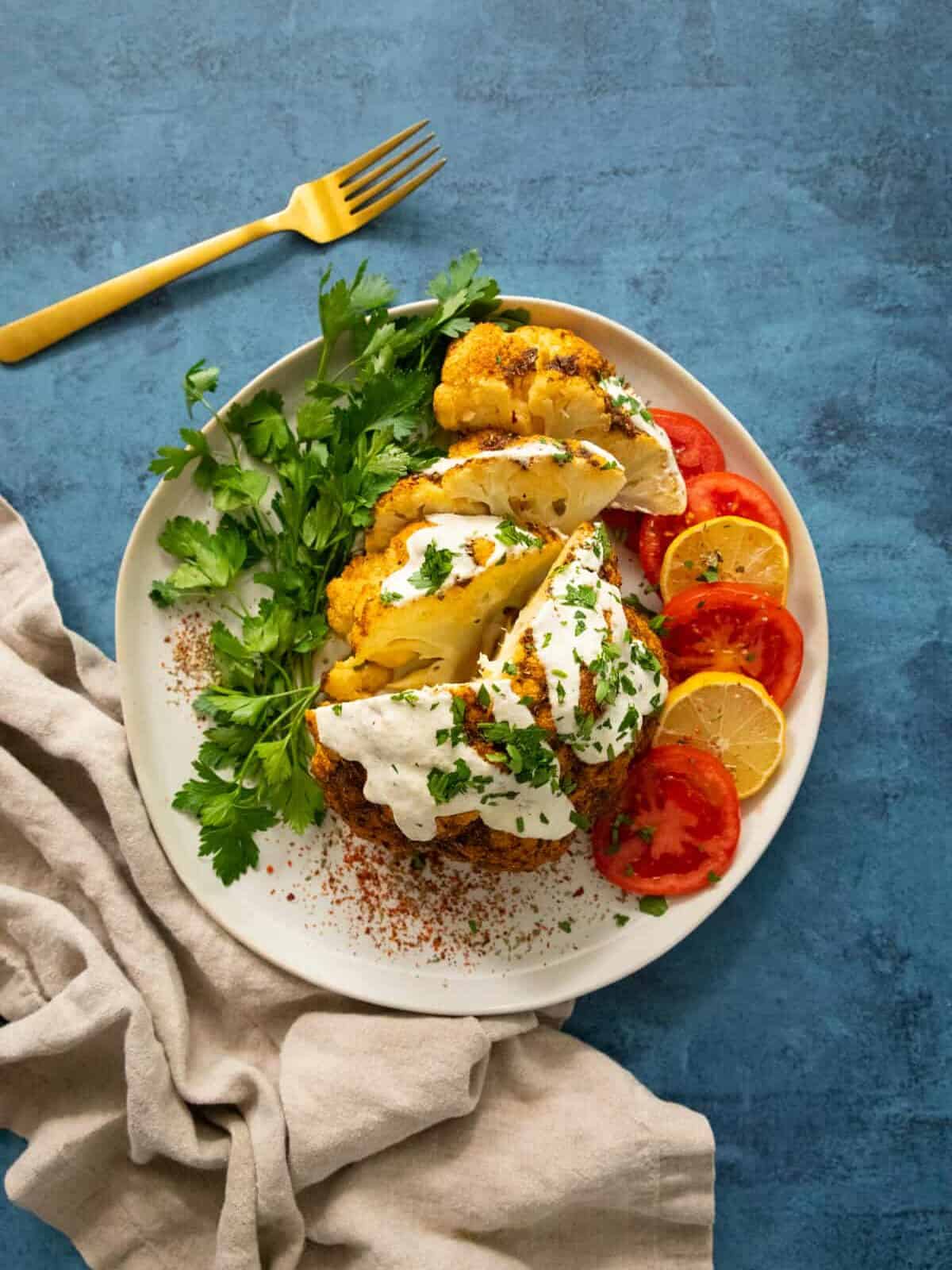 whole baked cauliflower on a white plate. 