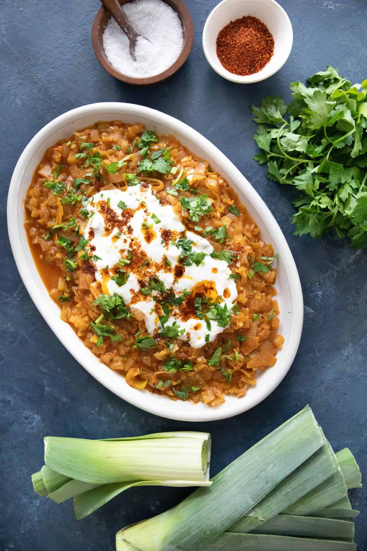 braised leeks on a platter topped with yogurt.