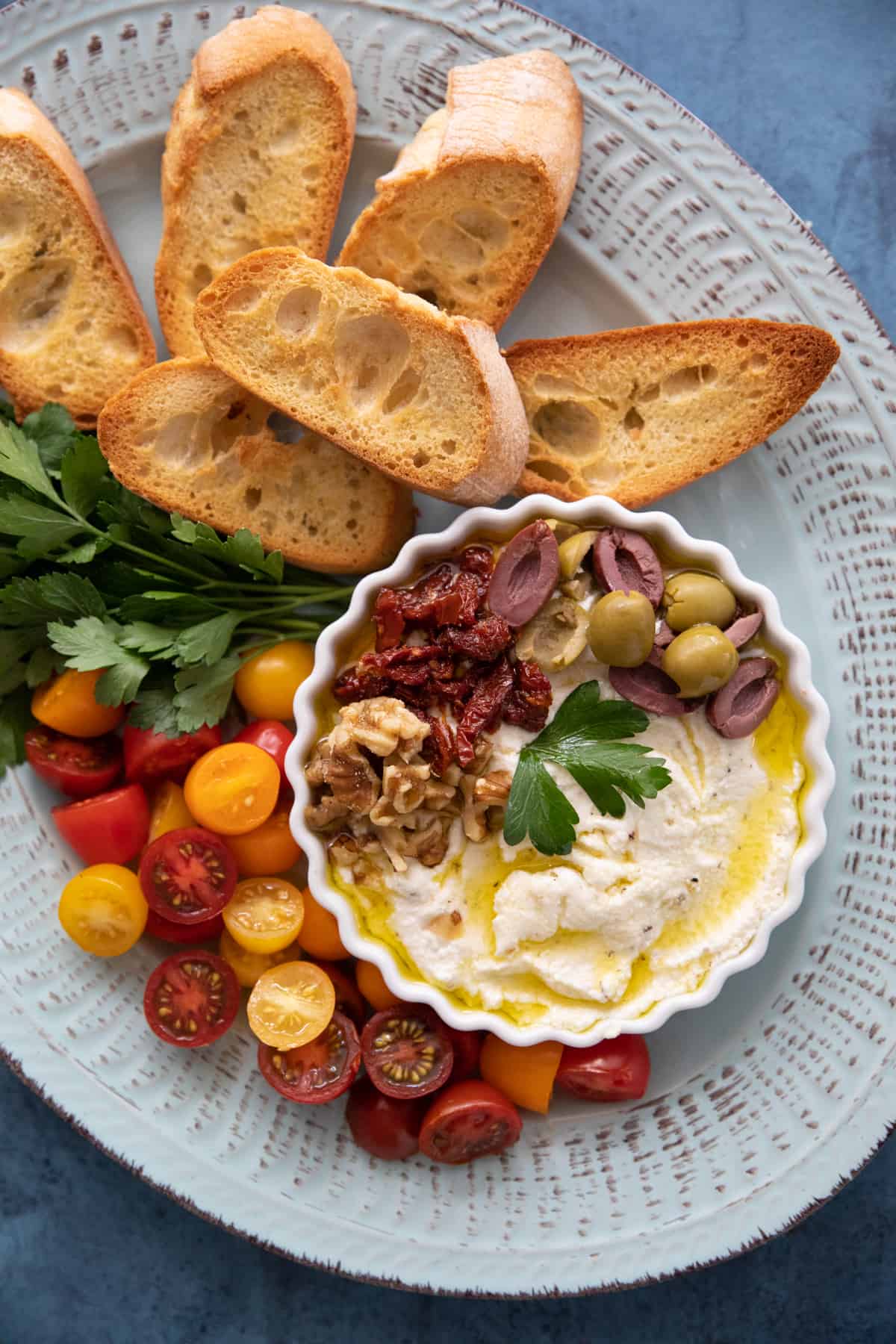 Whipped ricotta in a bowl with bread, tomatoes and herbs.