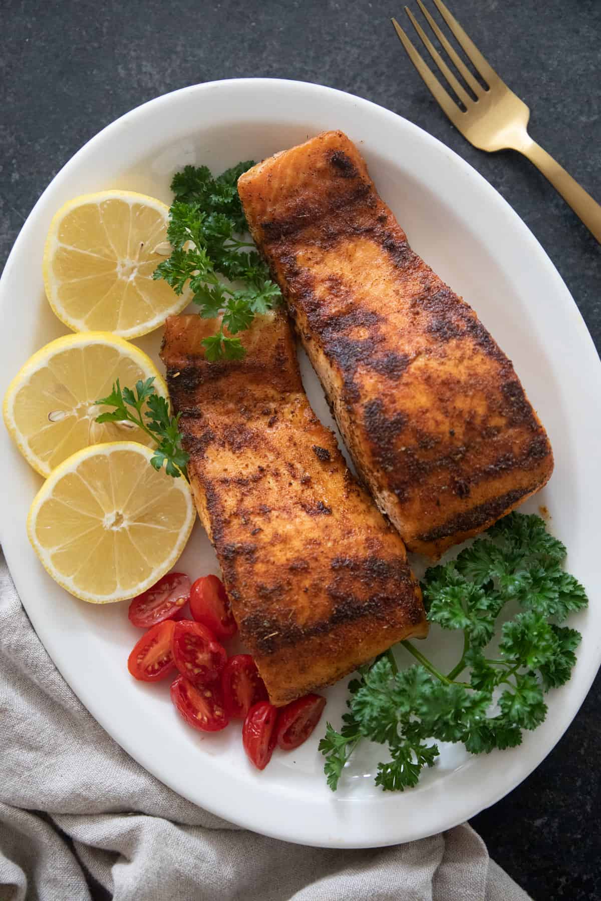 TWo pieces of blackened salmon on a plate. 