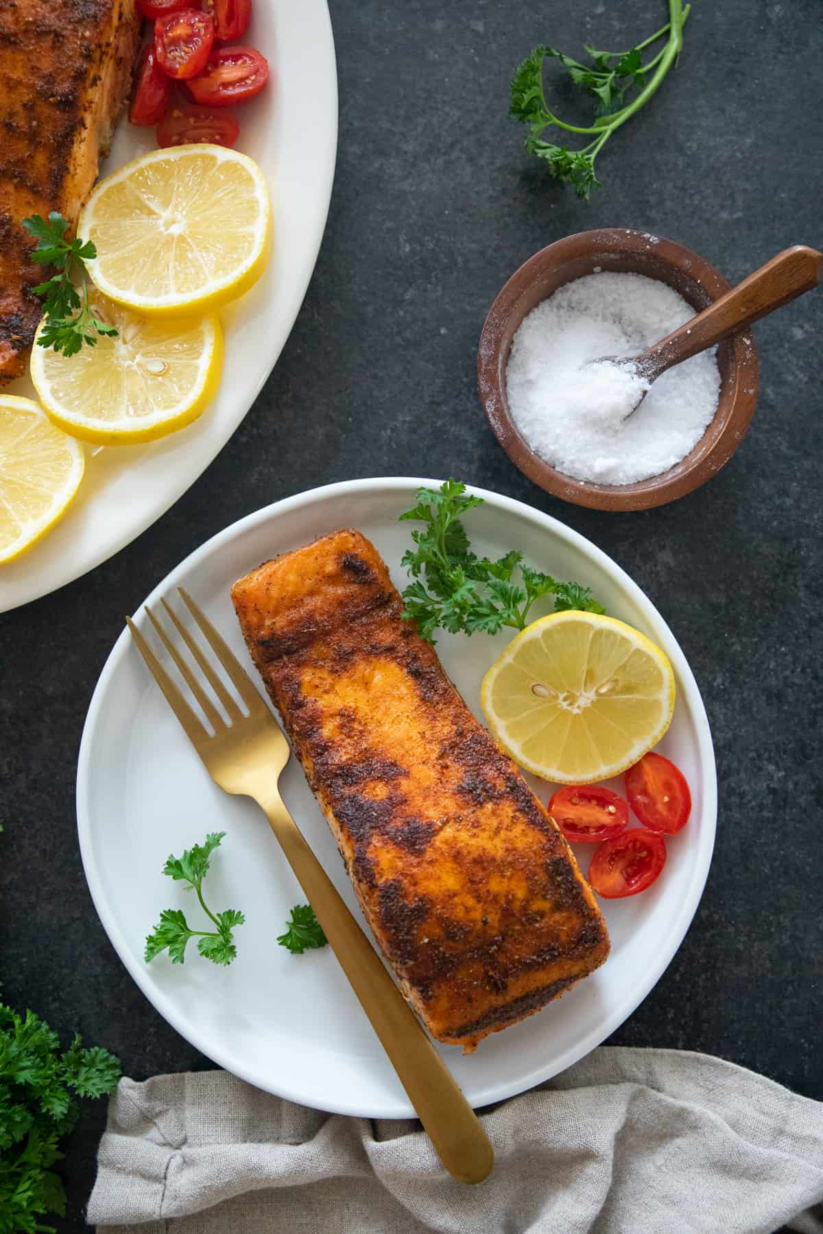 A piece of fish fillet on a plate with lemon and tomatoes. 