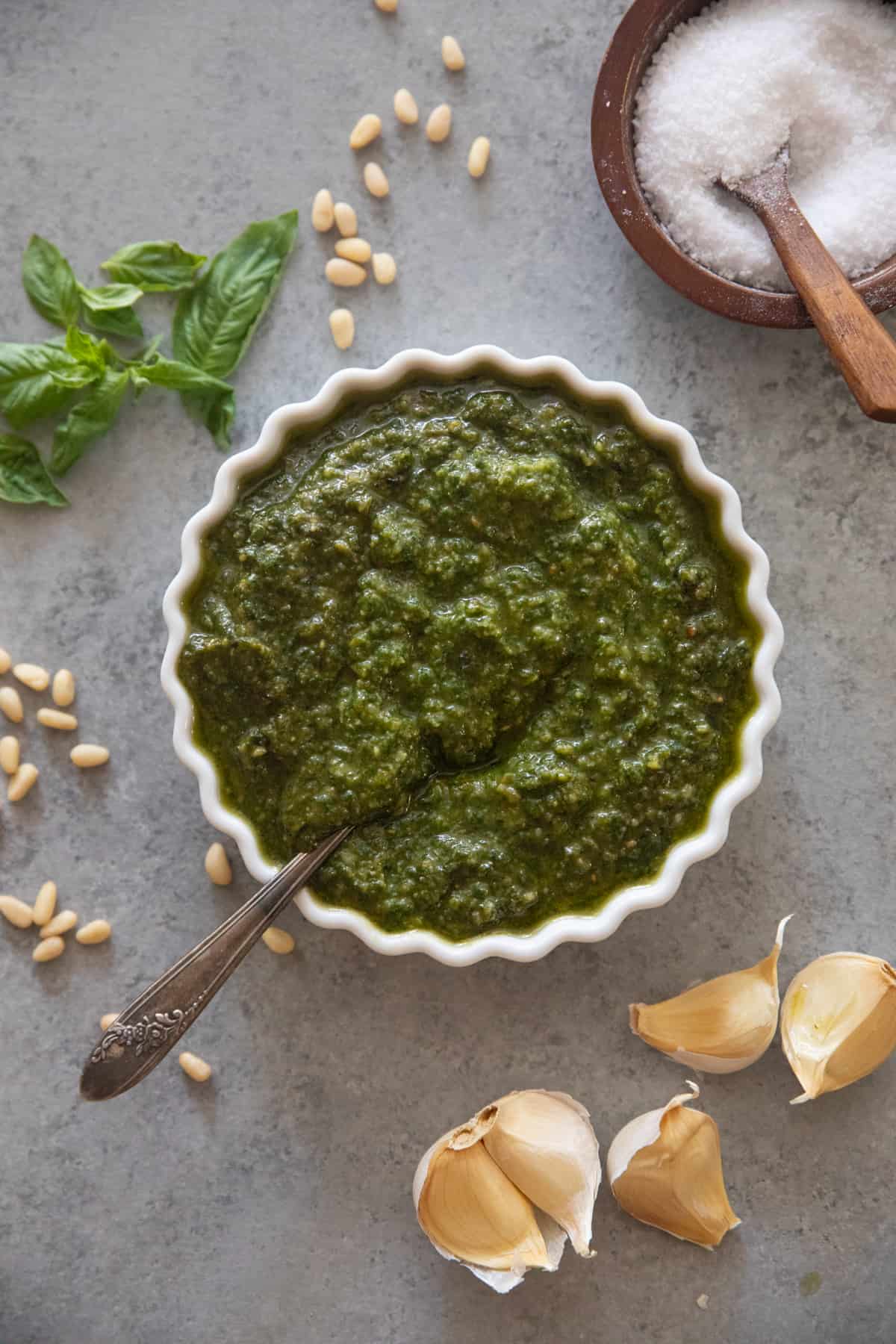 a bowl of basil pesto with a spoon in it. 