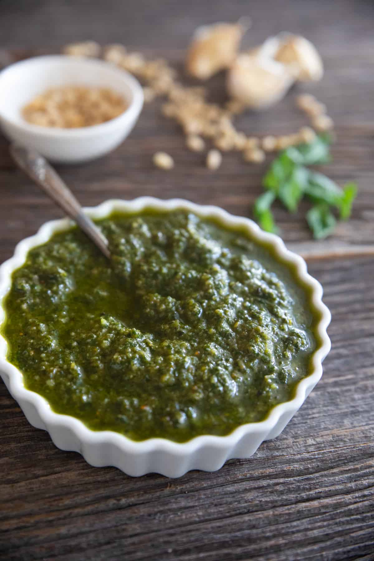 a bowl of homemade basil pesto on a wooden backdrop. 