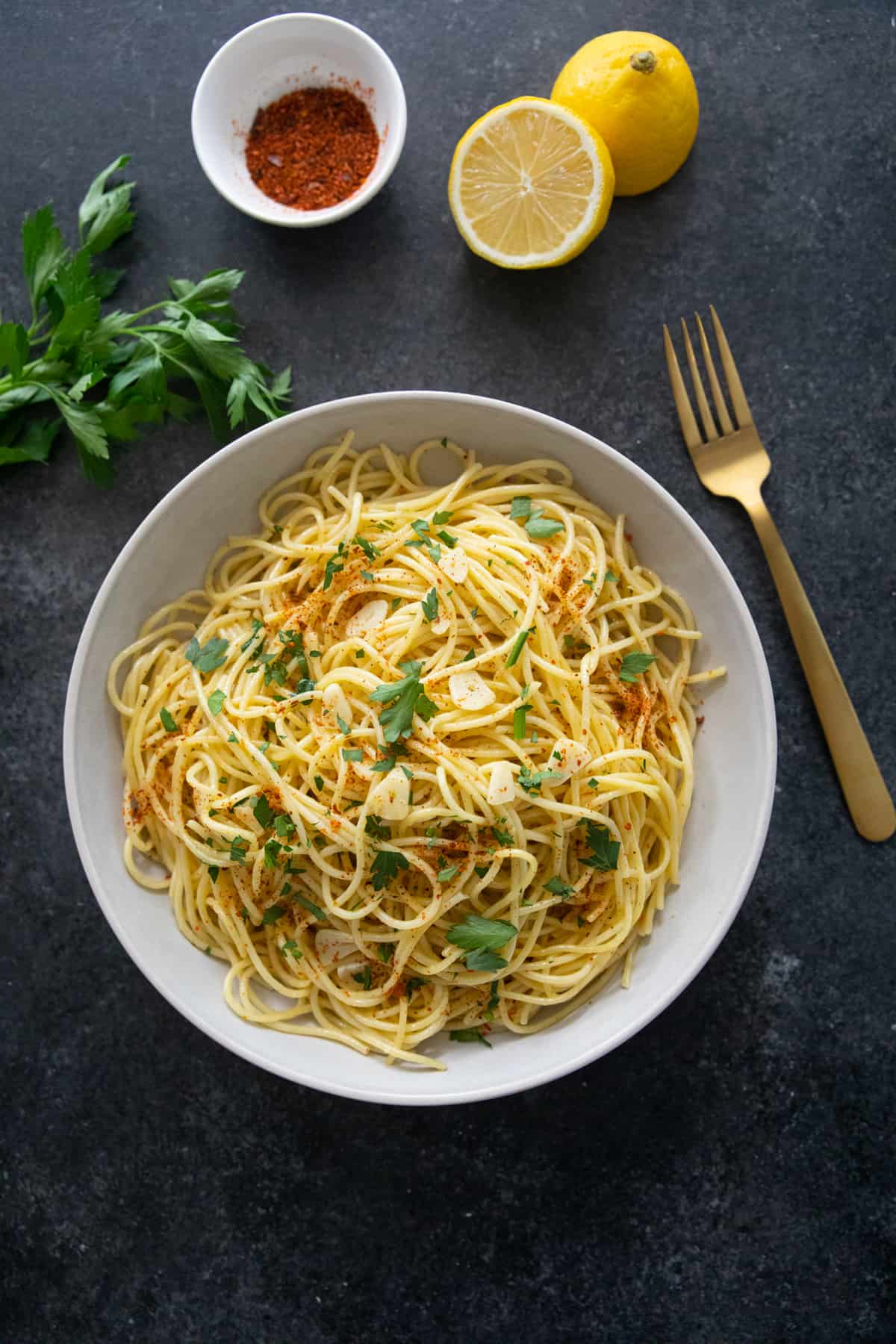 spaghetti aglio e olio in a bowl on a dark background.