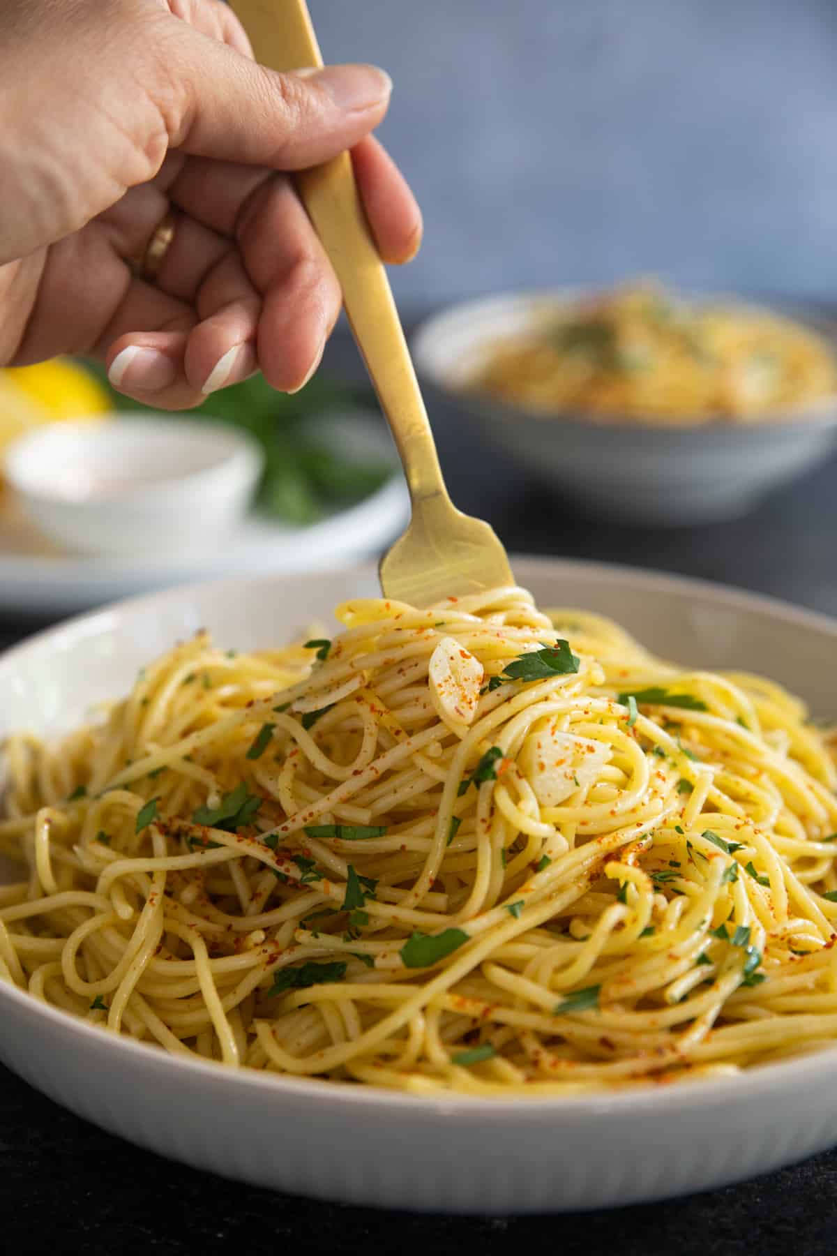 A gold fork into the spaghetti with garlic and olive oil.
