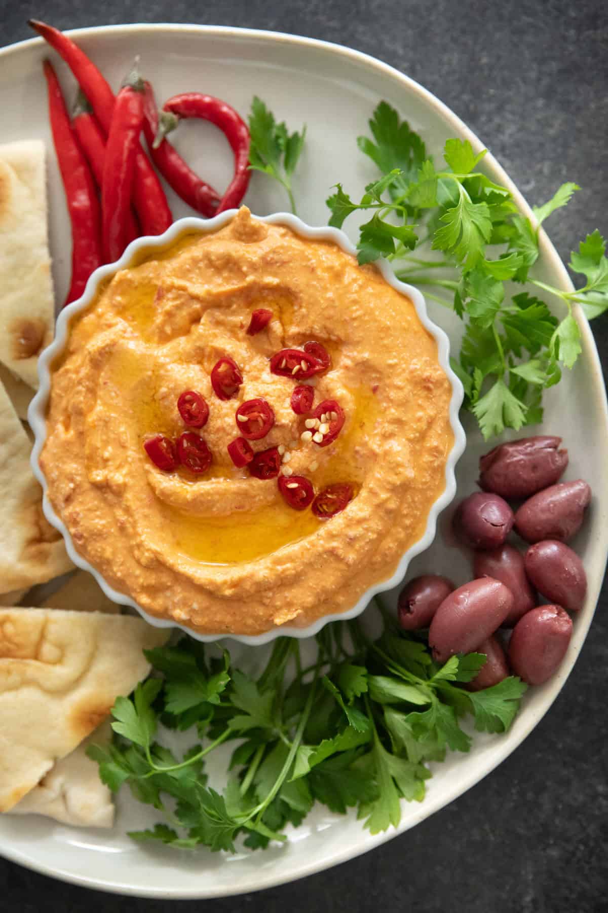 tirokafteri in a bowl with bread olives and herbs.