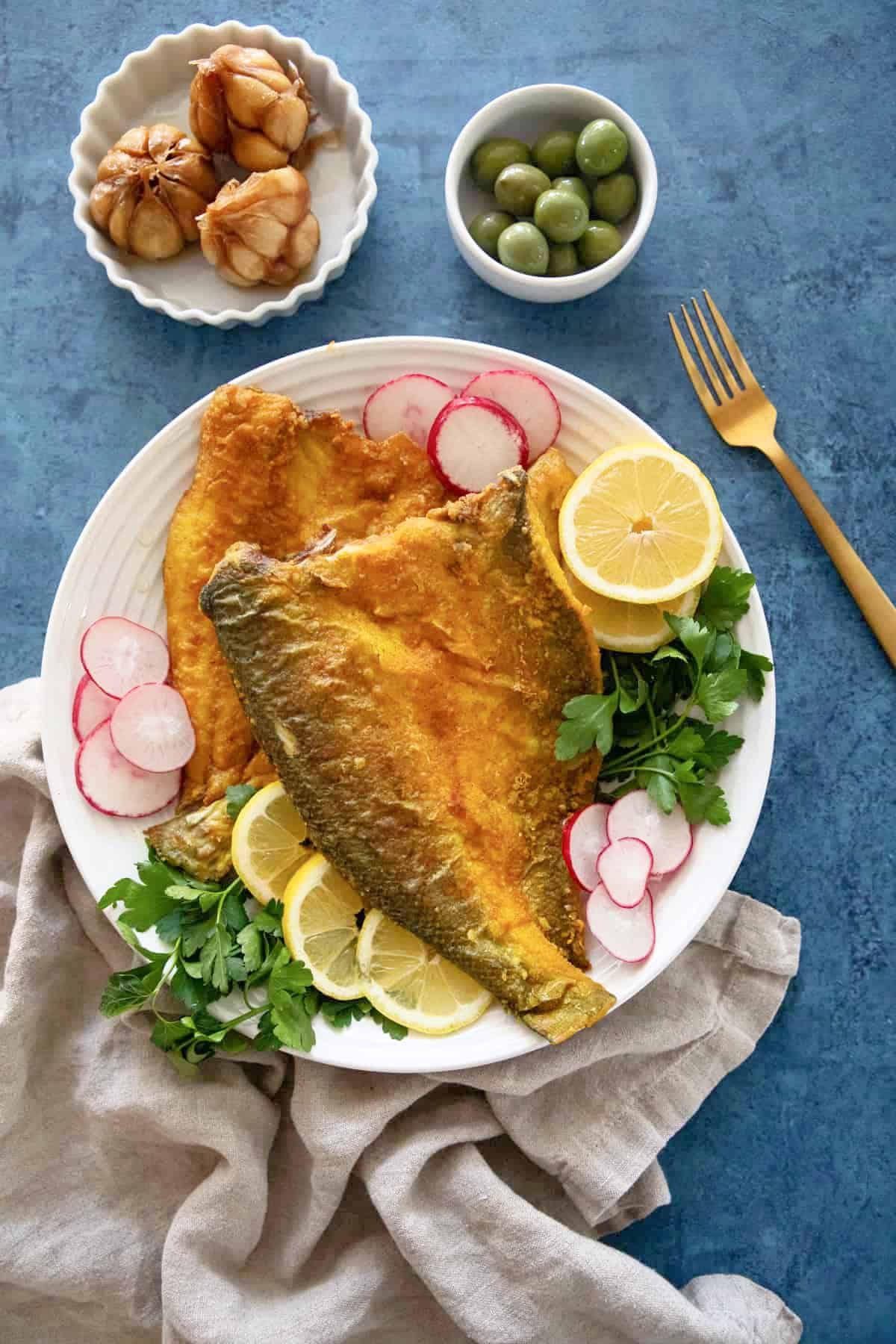Fried fish on a plate with blue backdrop. 